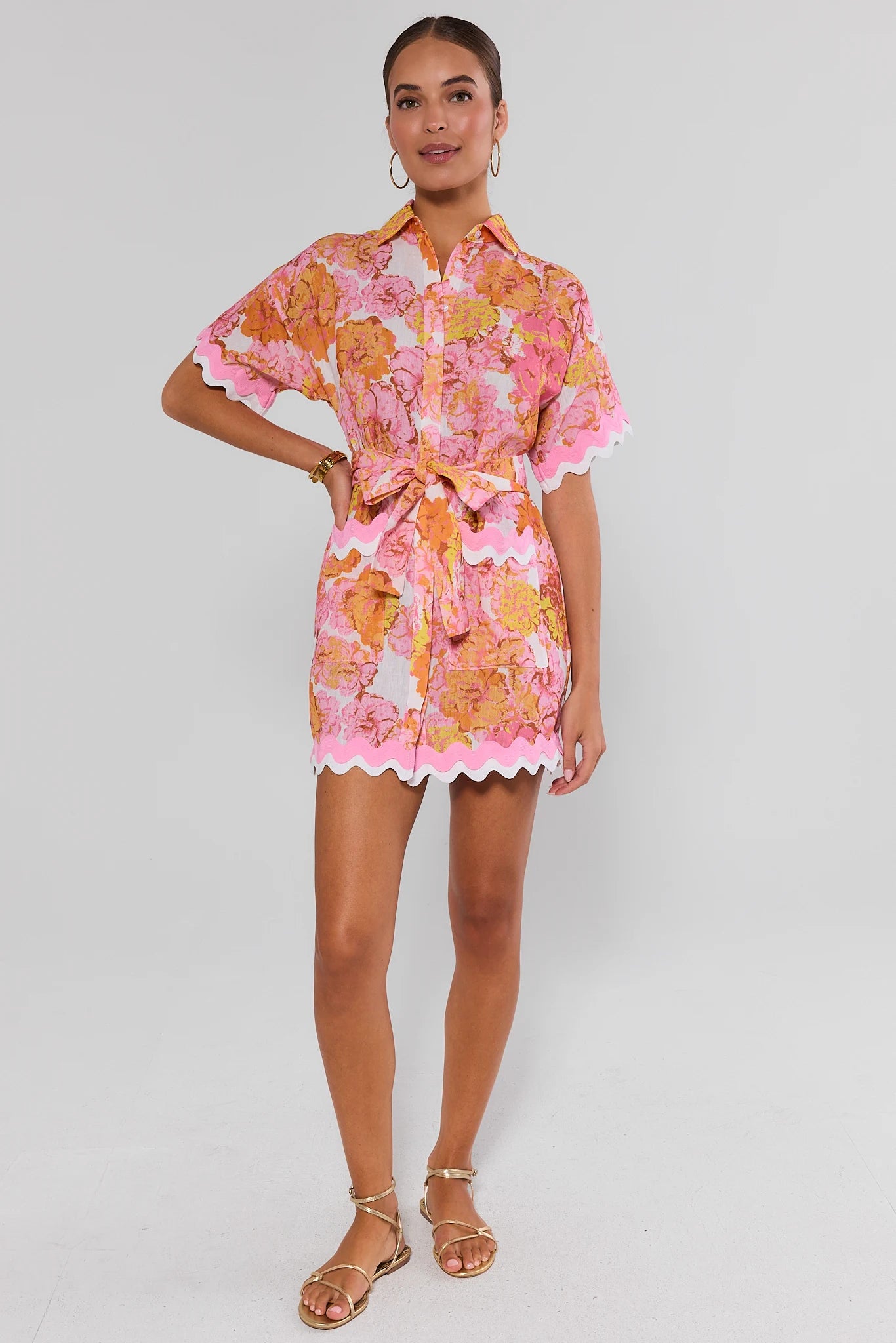 Woman wearing a colorful floral dress on a white background walking