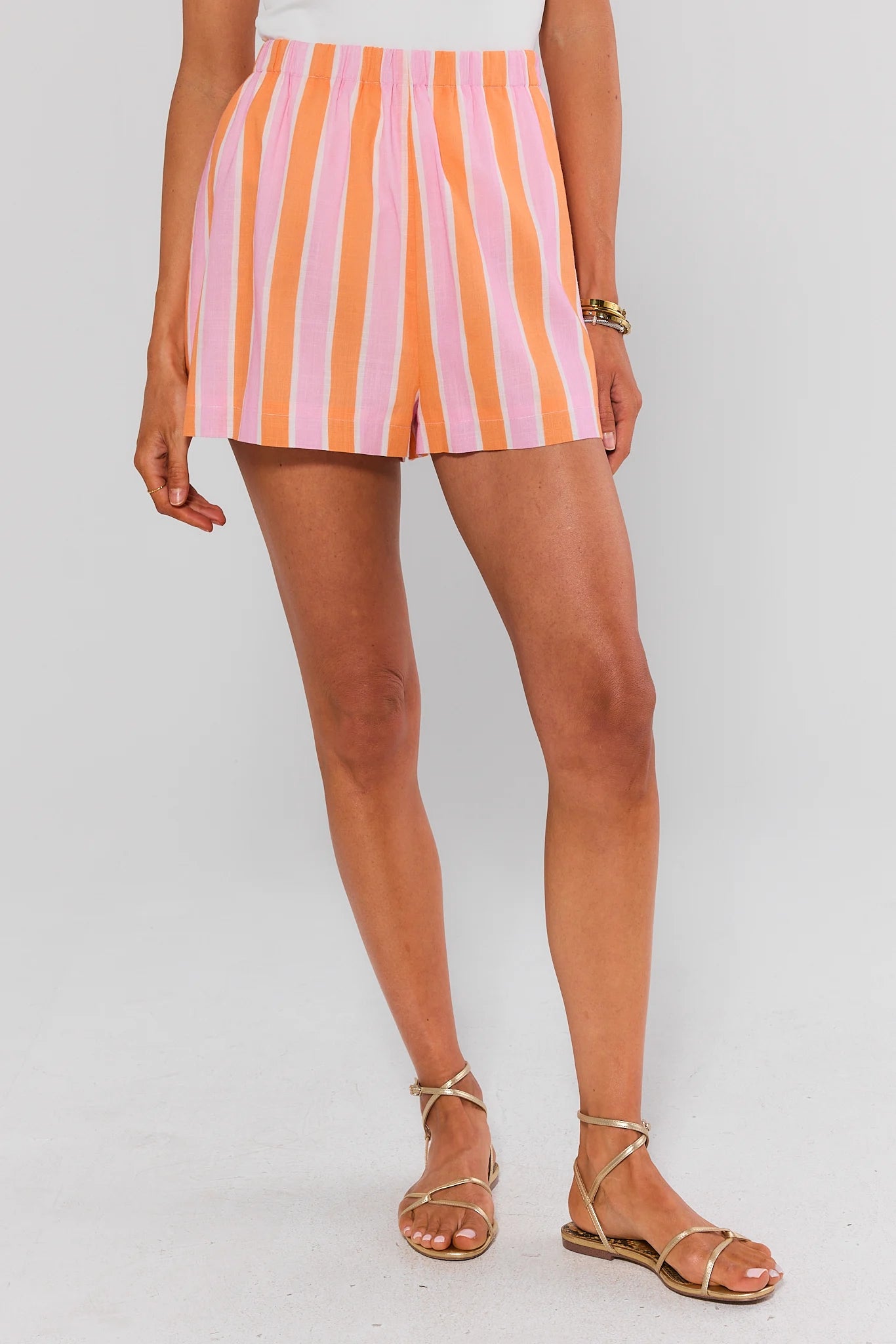Person wearing a striped skirt with pink and orange horizontal stripes on a white background