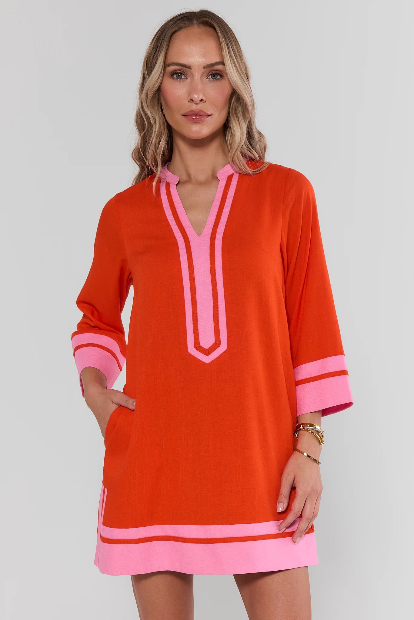 Woman wearing an orange and pink dress with a plain background