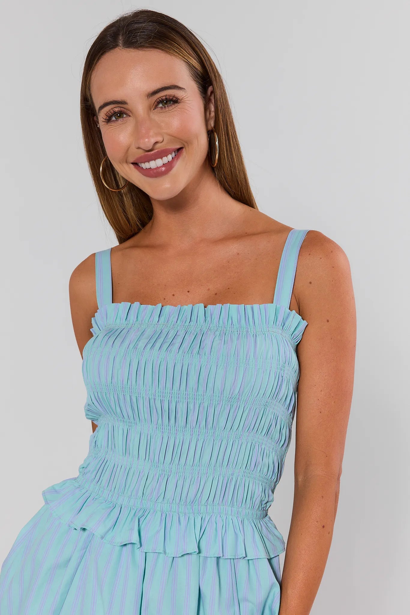 Woman wearing a light blue dress with thin straps against a plain background close up