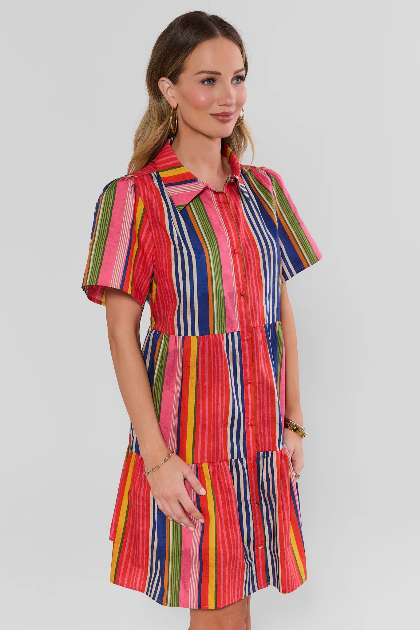 Woman wearing a colorful striped dress on a white background side shot