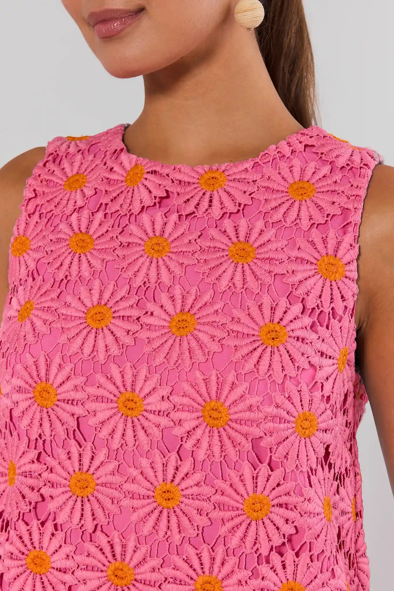 Close-up of a pink lace dress with orange floral patterns on a plain background