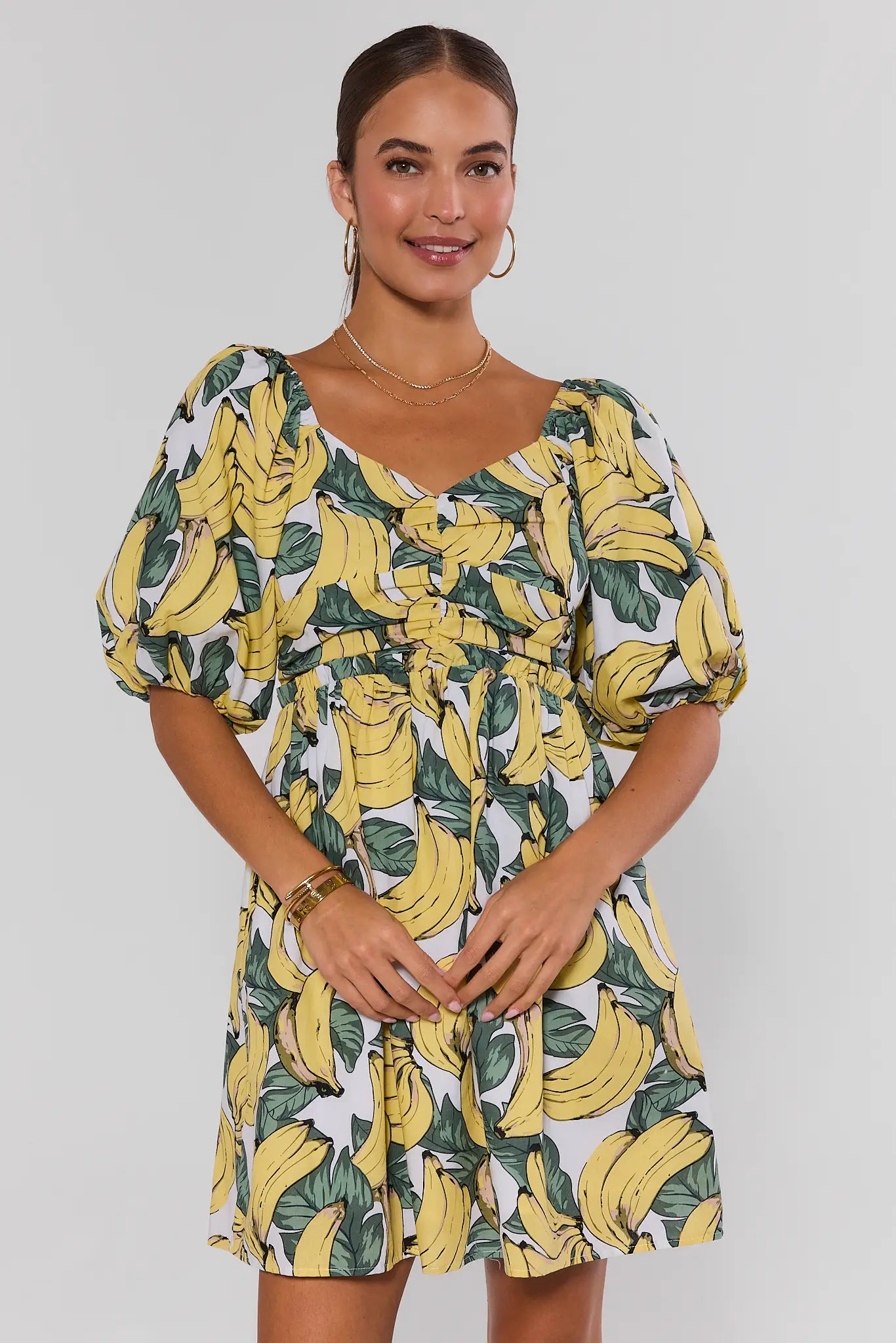Woman wearing a dress with banana print against a plain background