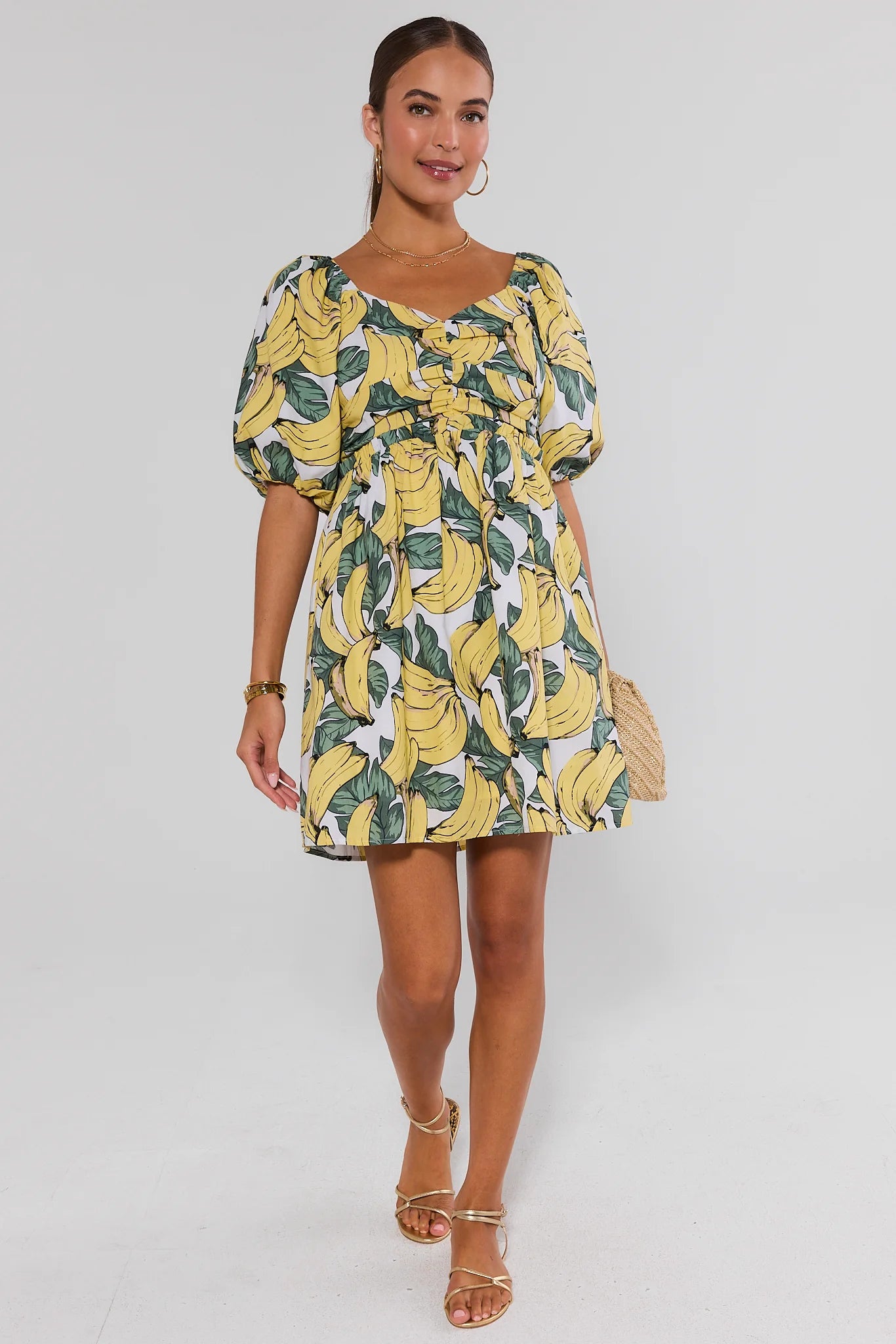 Woman wearing a banana print dress on a white background standing