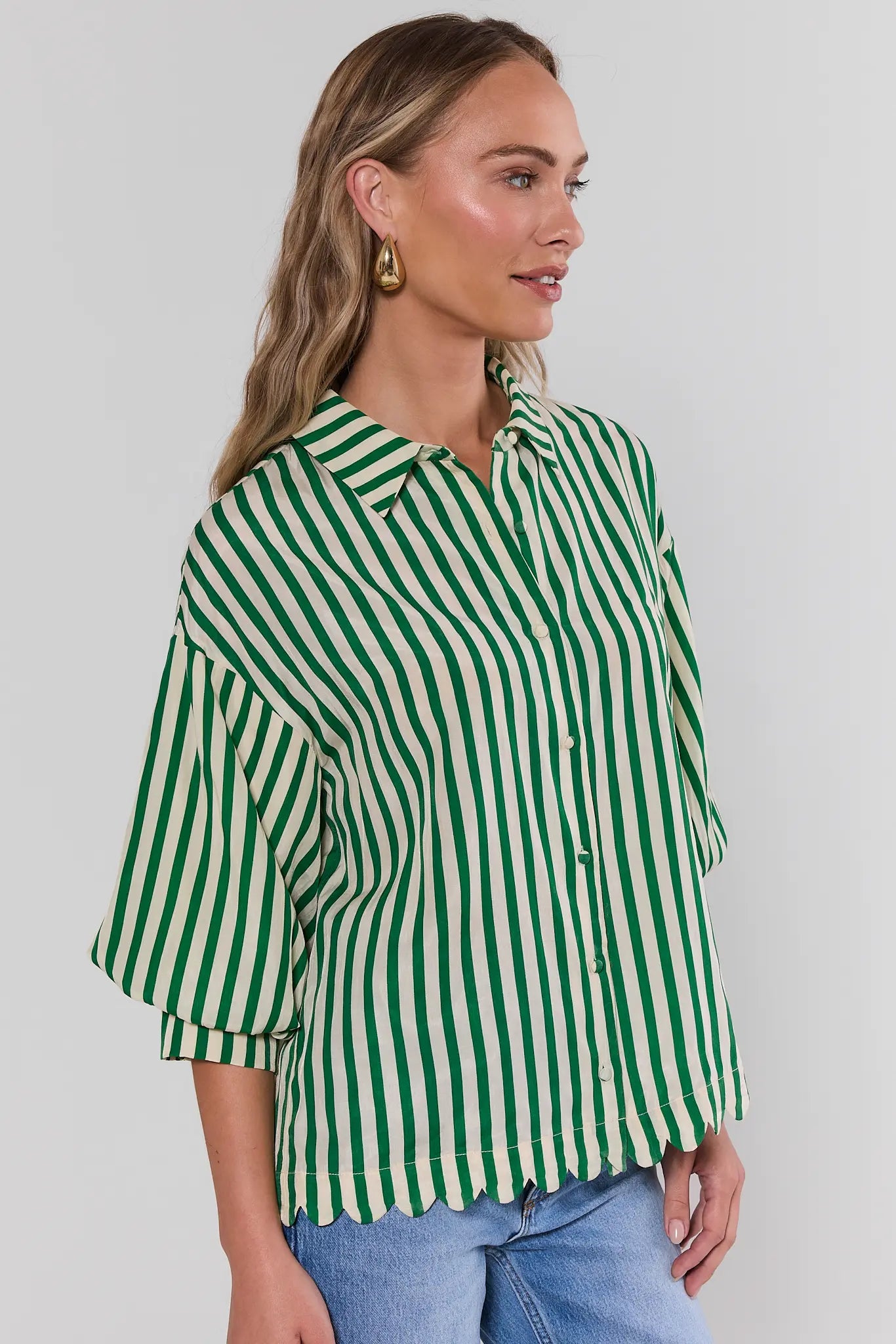 Woman wearing a green and white striped shirt against a plain background side