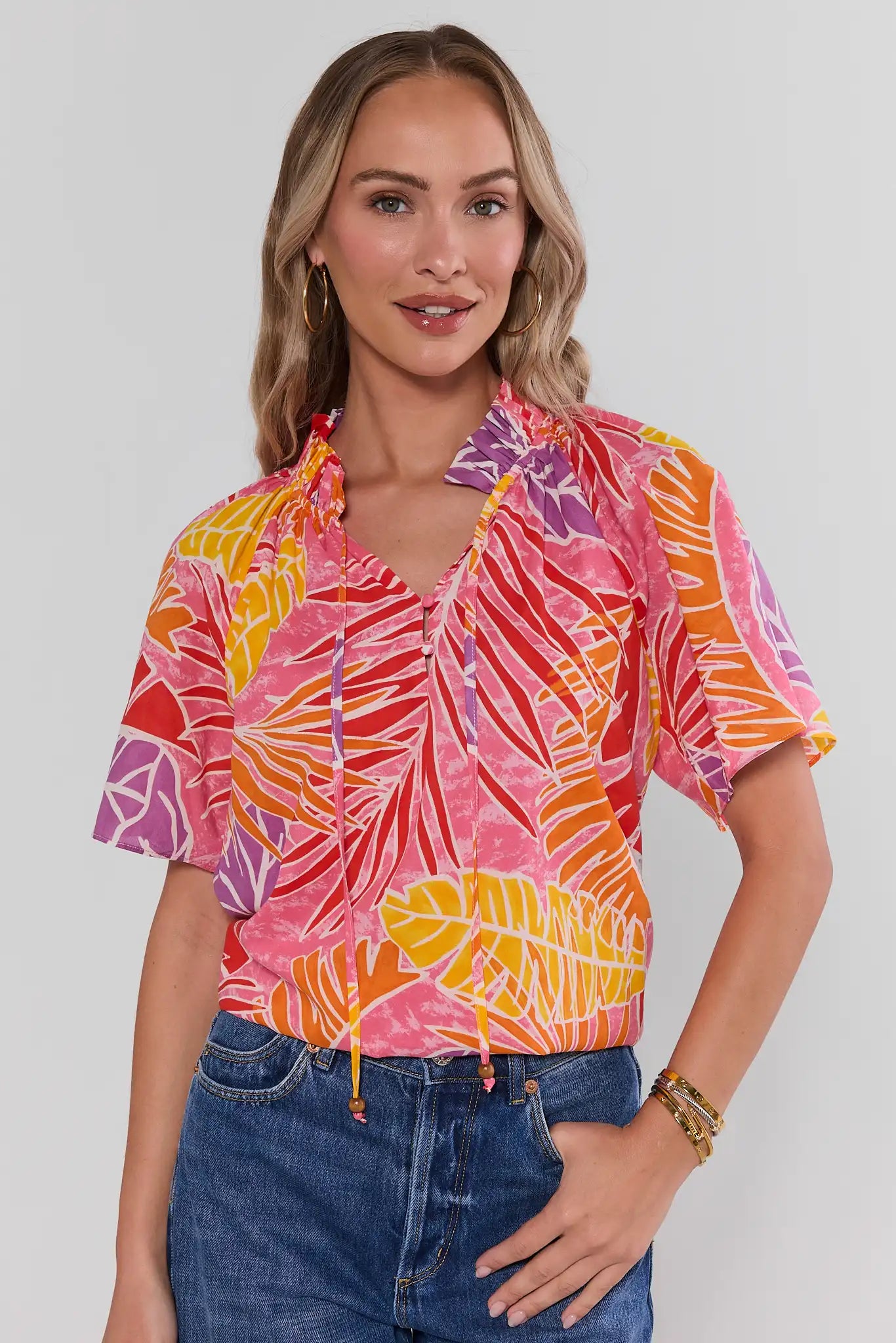 Woman wearing a colorful patterned shirt with a plain background standing