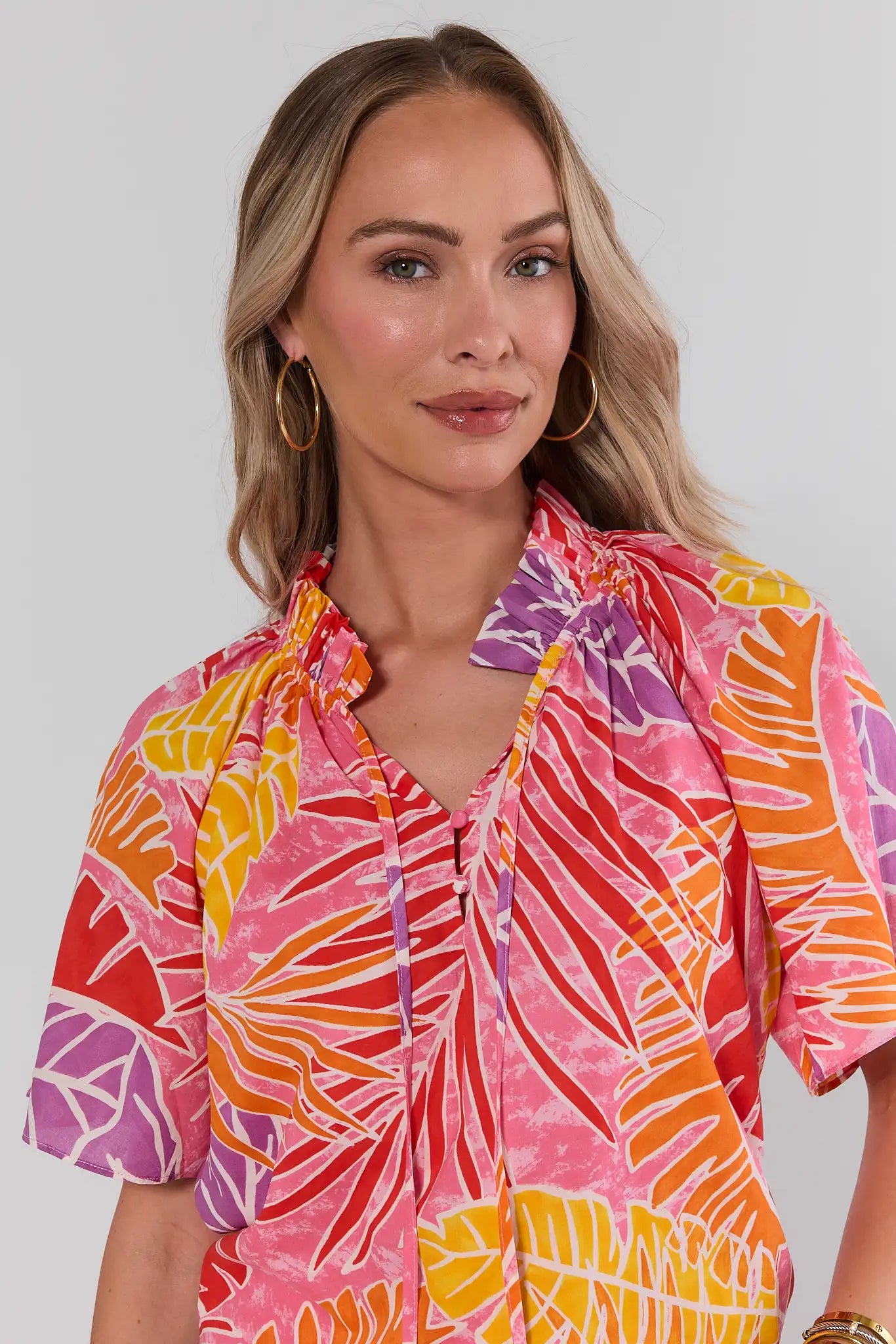 Woman wearing a colorful patterned shirt against a plain background close up