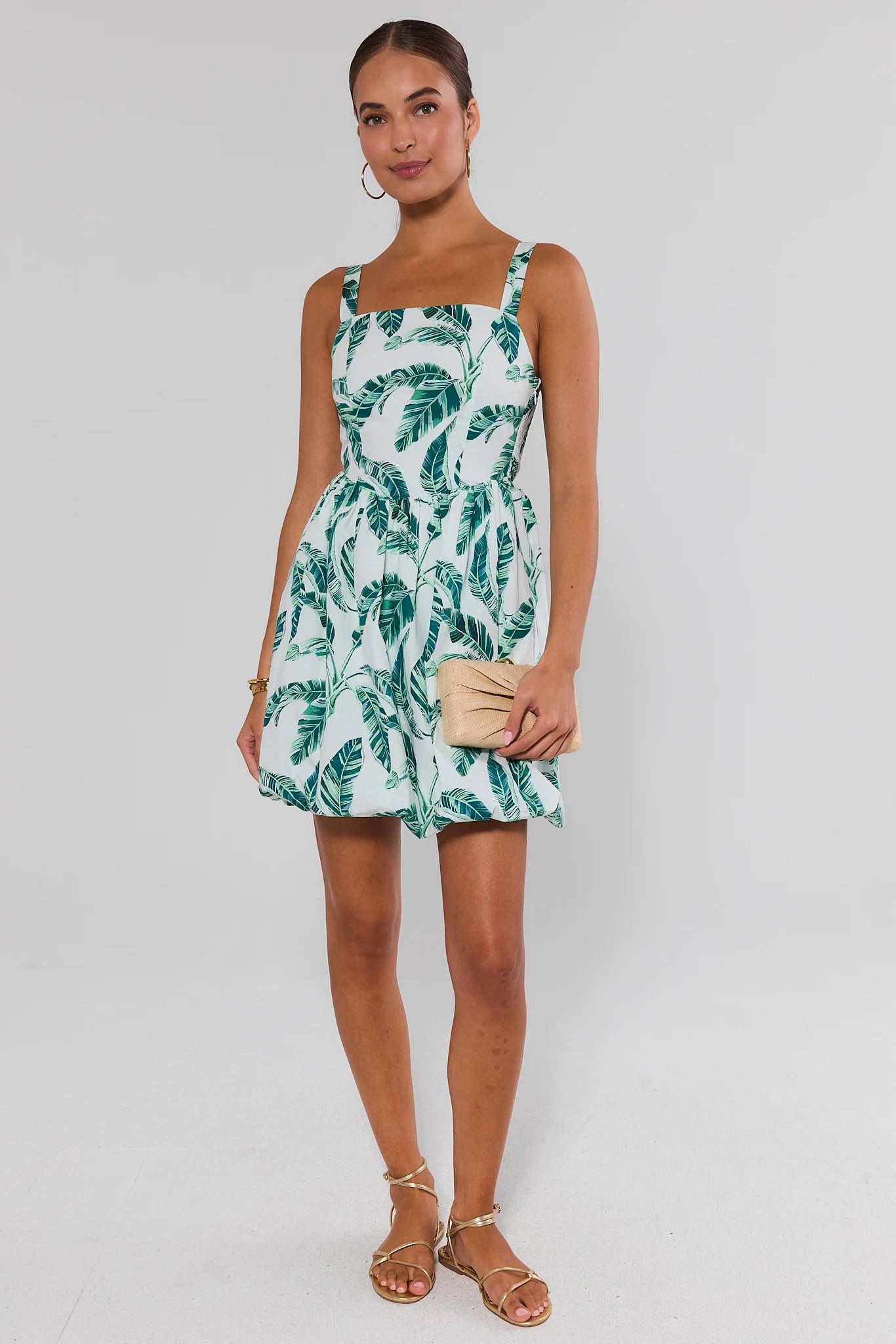 Woman wearing a tropical leaf pattern dress on a plain background standing
