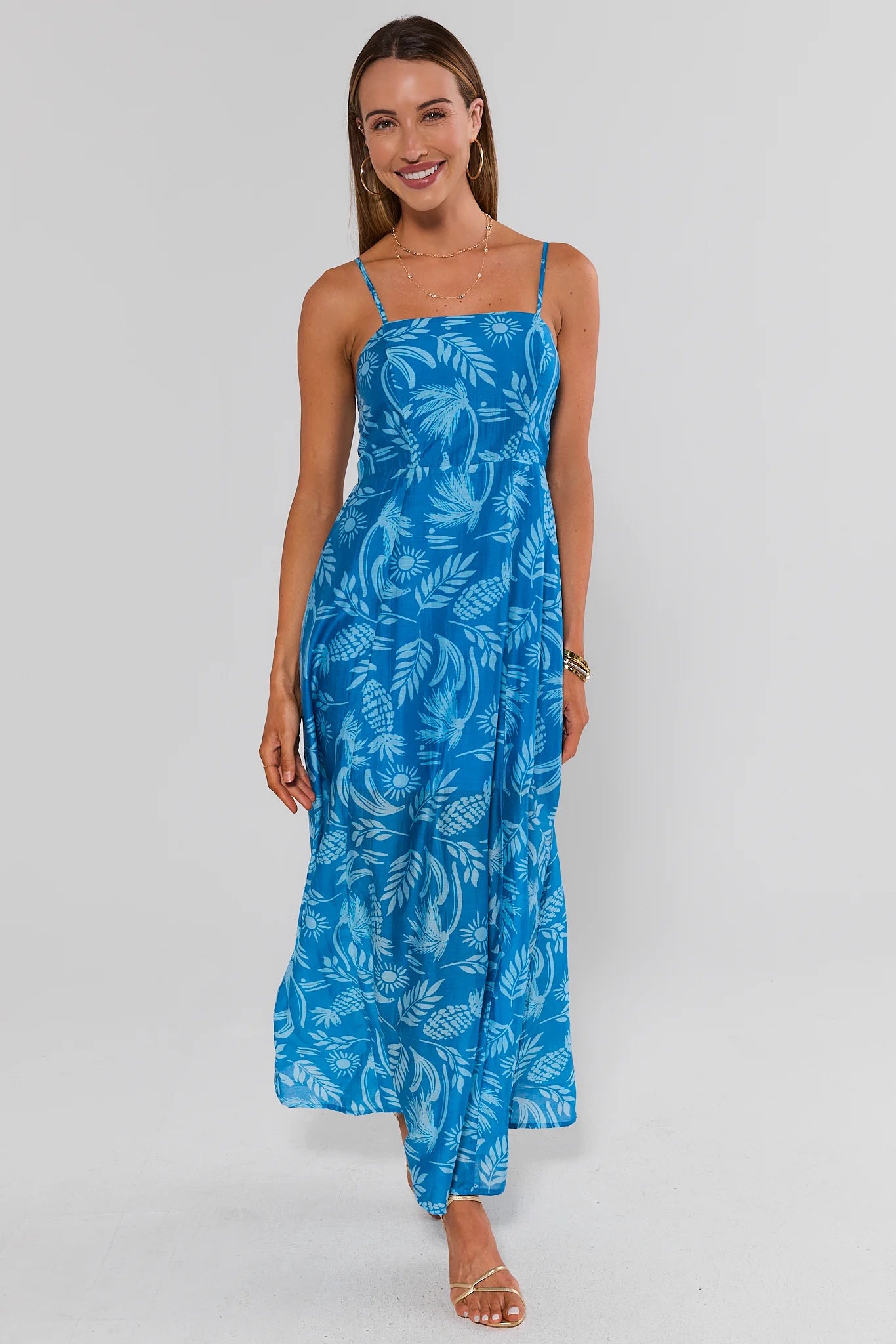 Woman wearing a blue floral dress on a white background standing