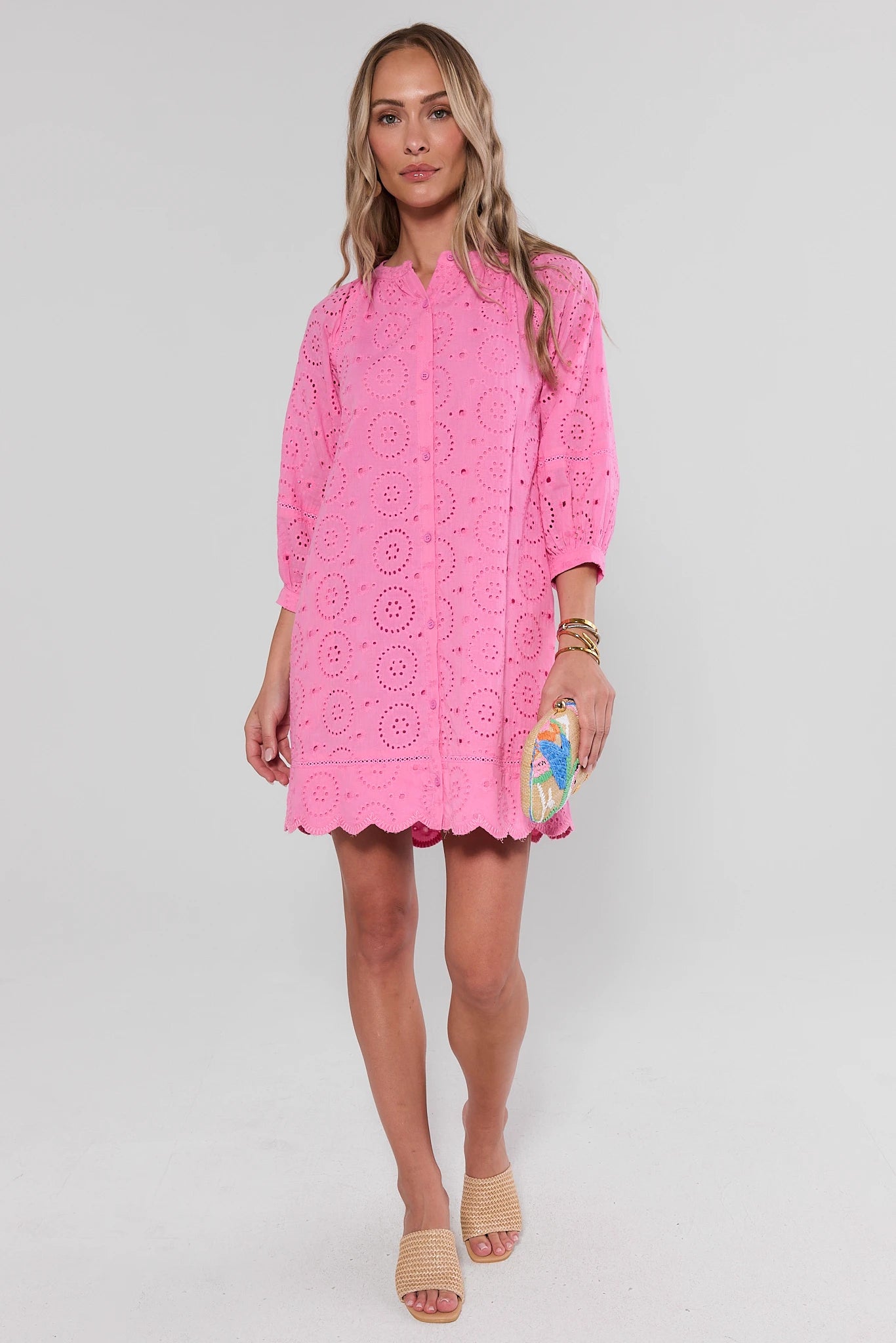 Woman standing wearing a pink lace dress on a white background
