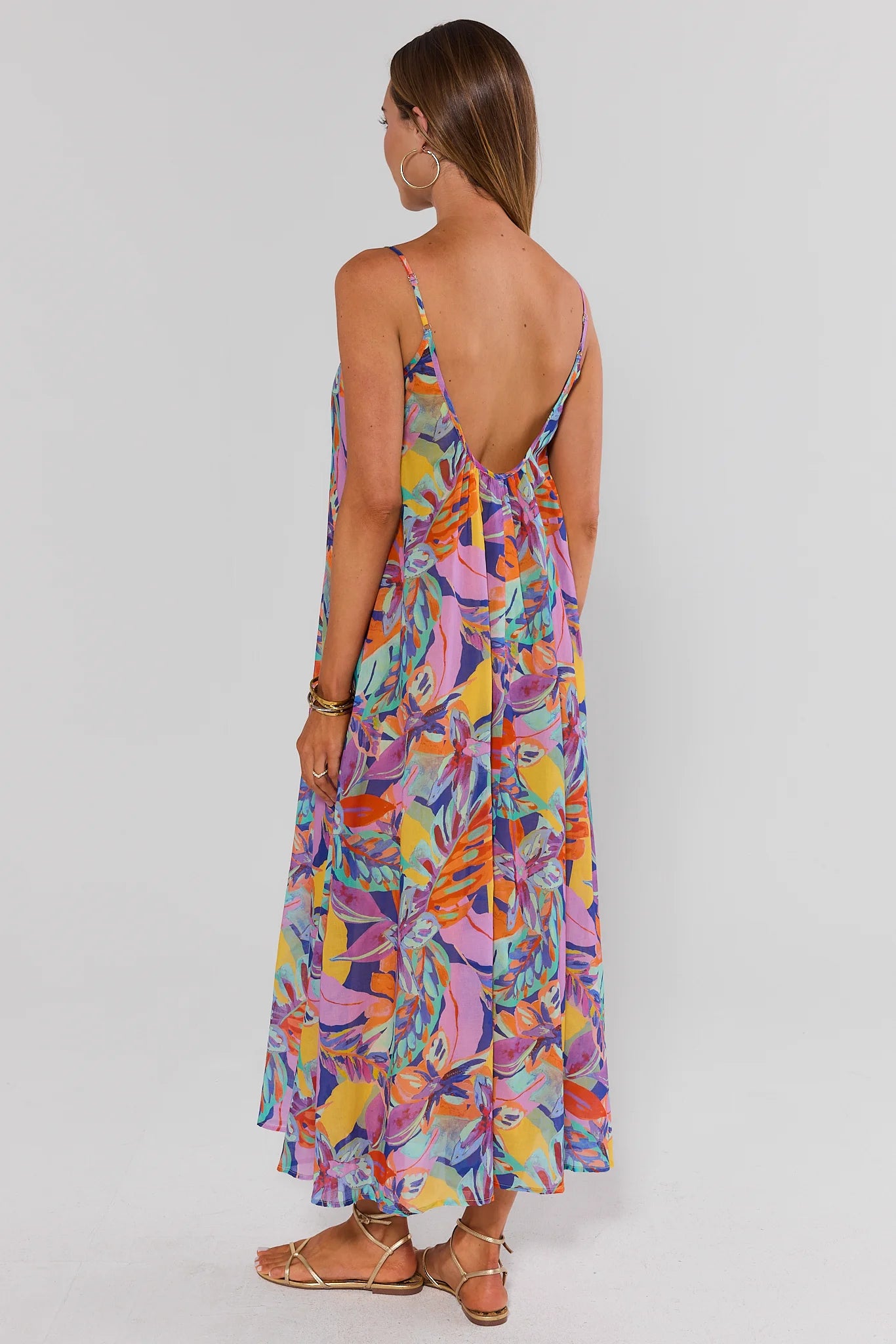 Woman wearing a colorful floral dress on a plain background back