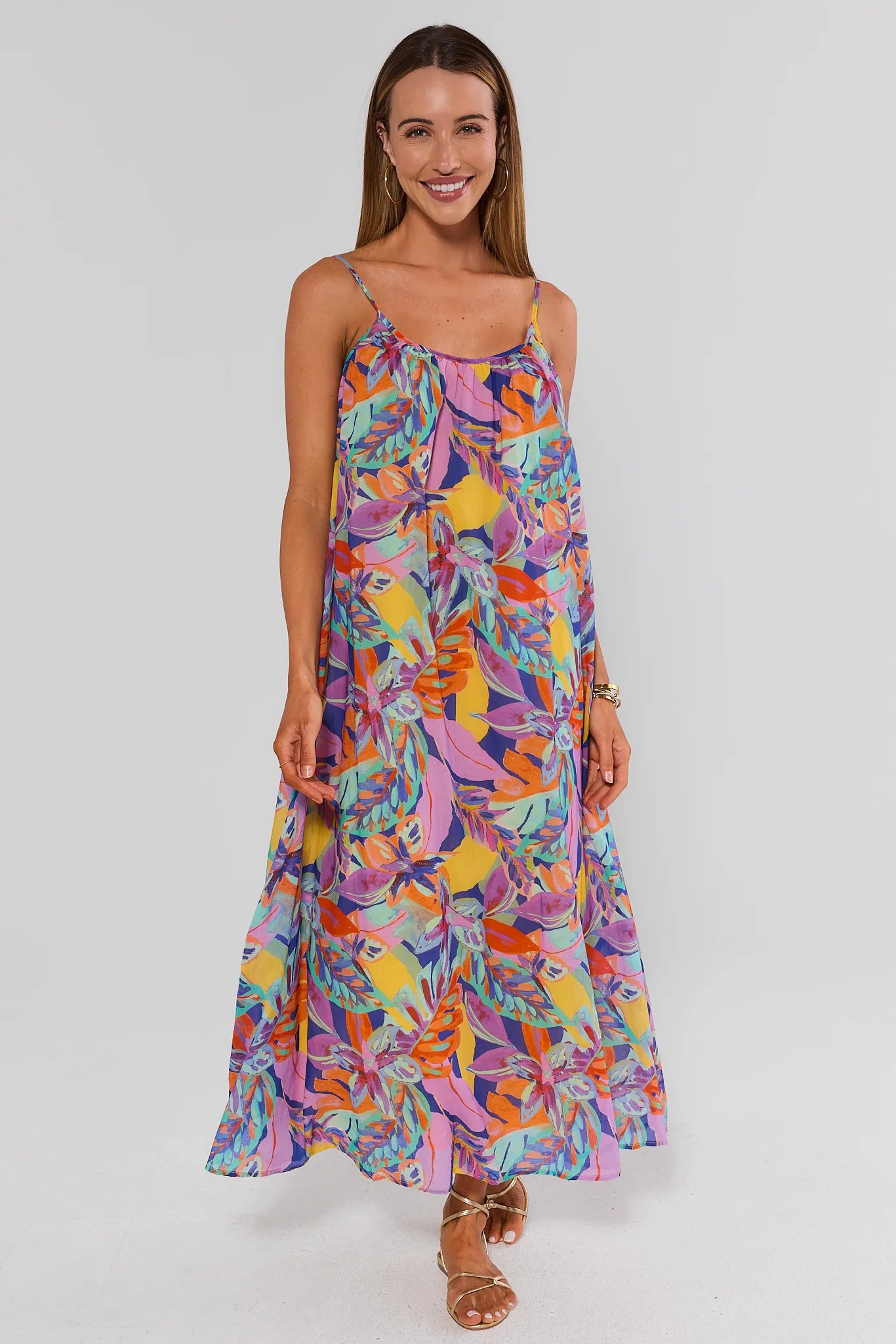 Woman wearing a colorful floral dress on a plain background walking