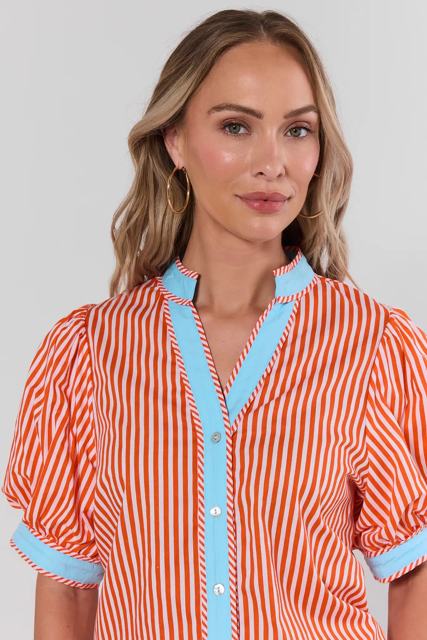 close up Woman wearing a red and white striped shirt with blue trim on a plain background