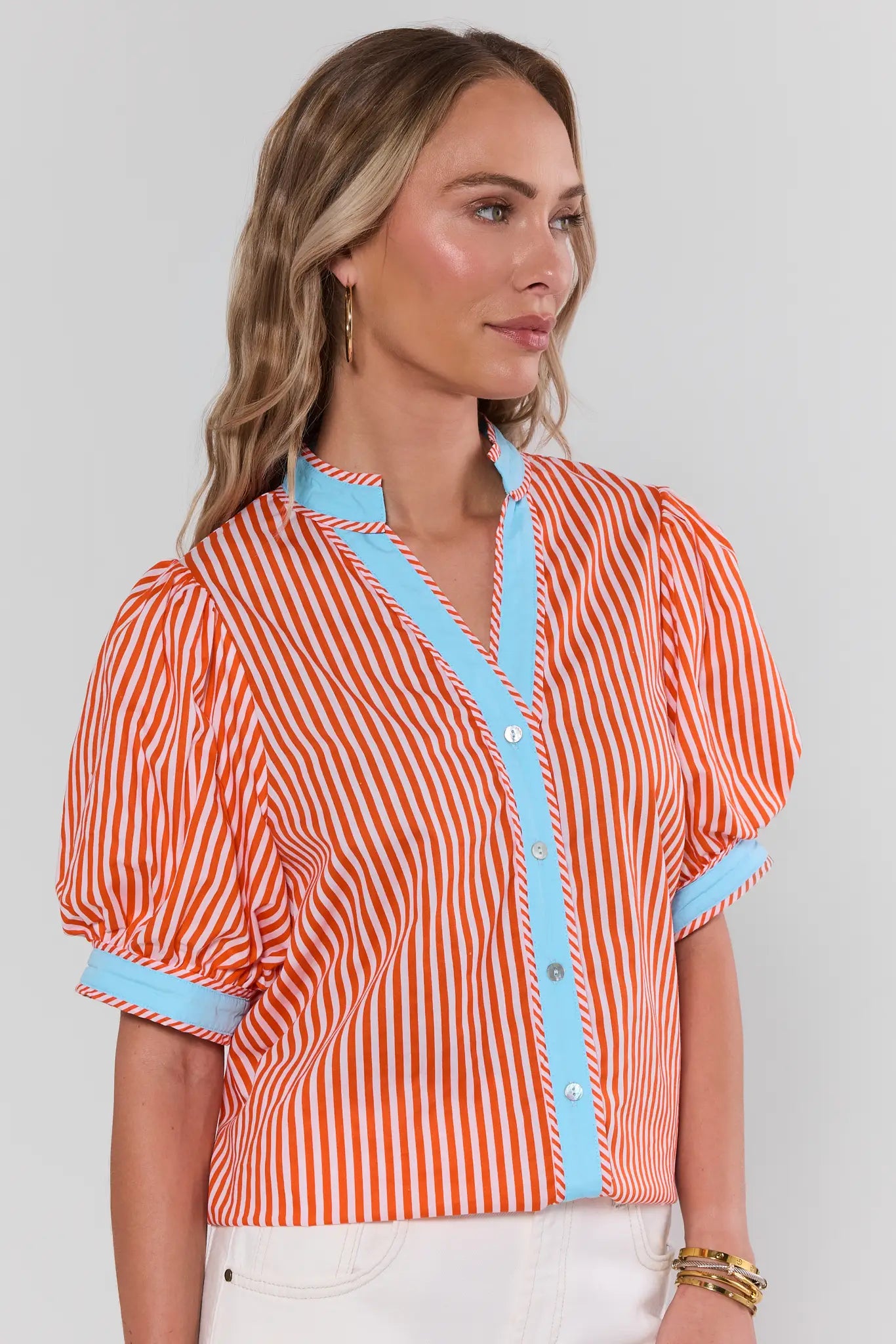 Woman wearing a red and white striped shirt with blue accents on a plain background