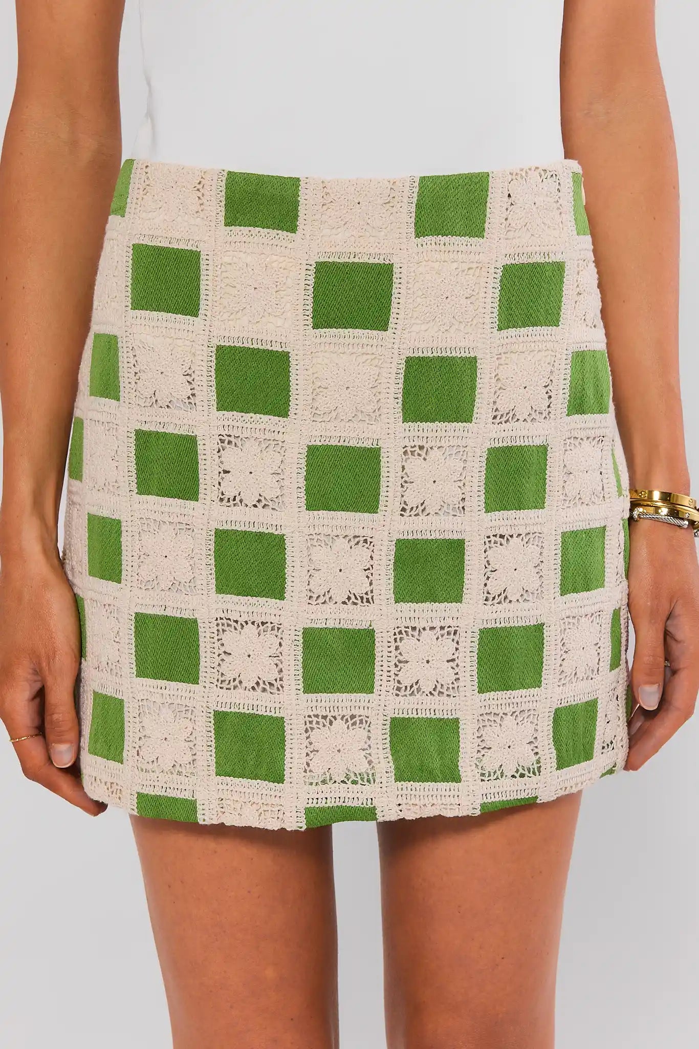Green and beige checkered skirt worn by a person on a plain background