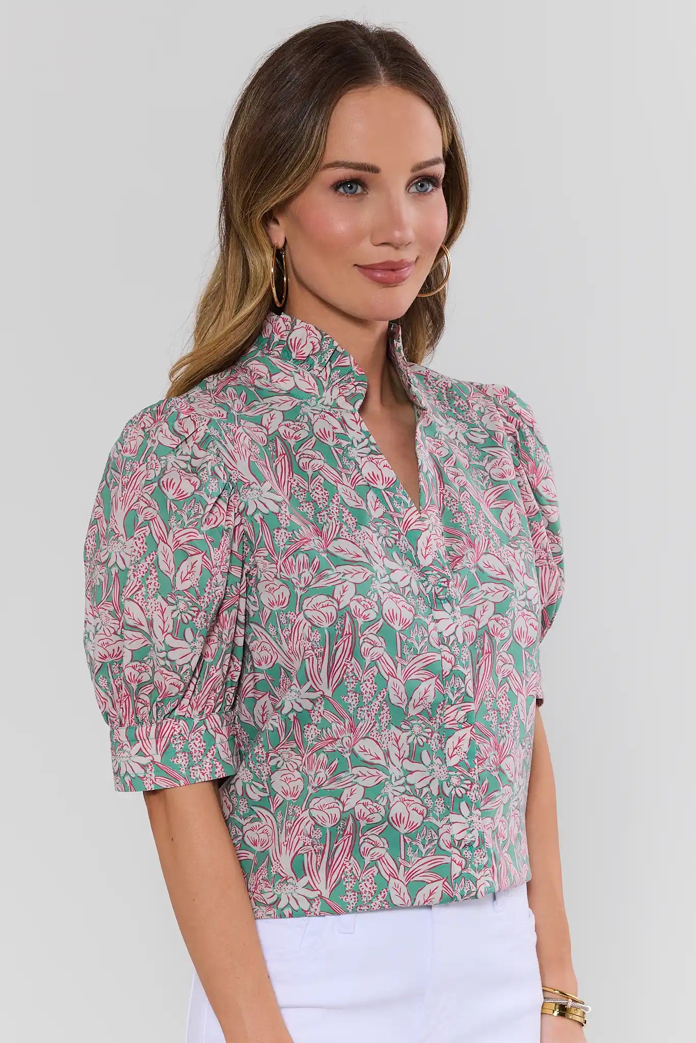 Woman wearing a pink and green floral blouse against a white background side
