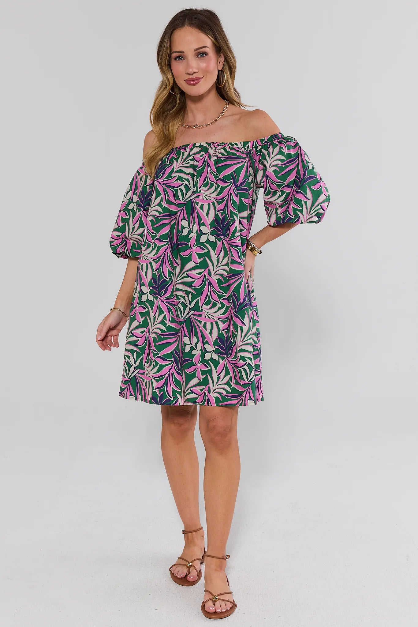 Woman wearing a tropical leaf patterned dress on a white background standing