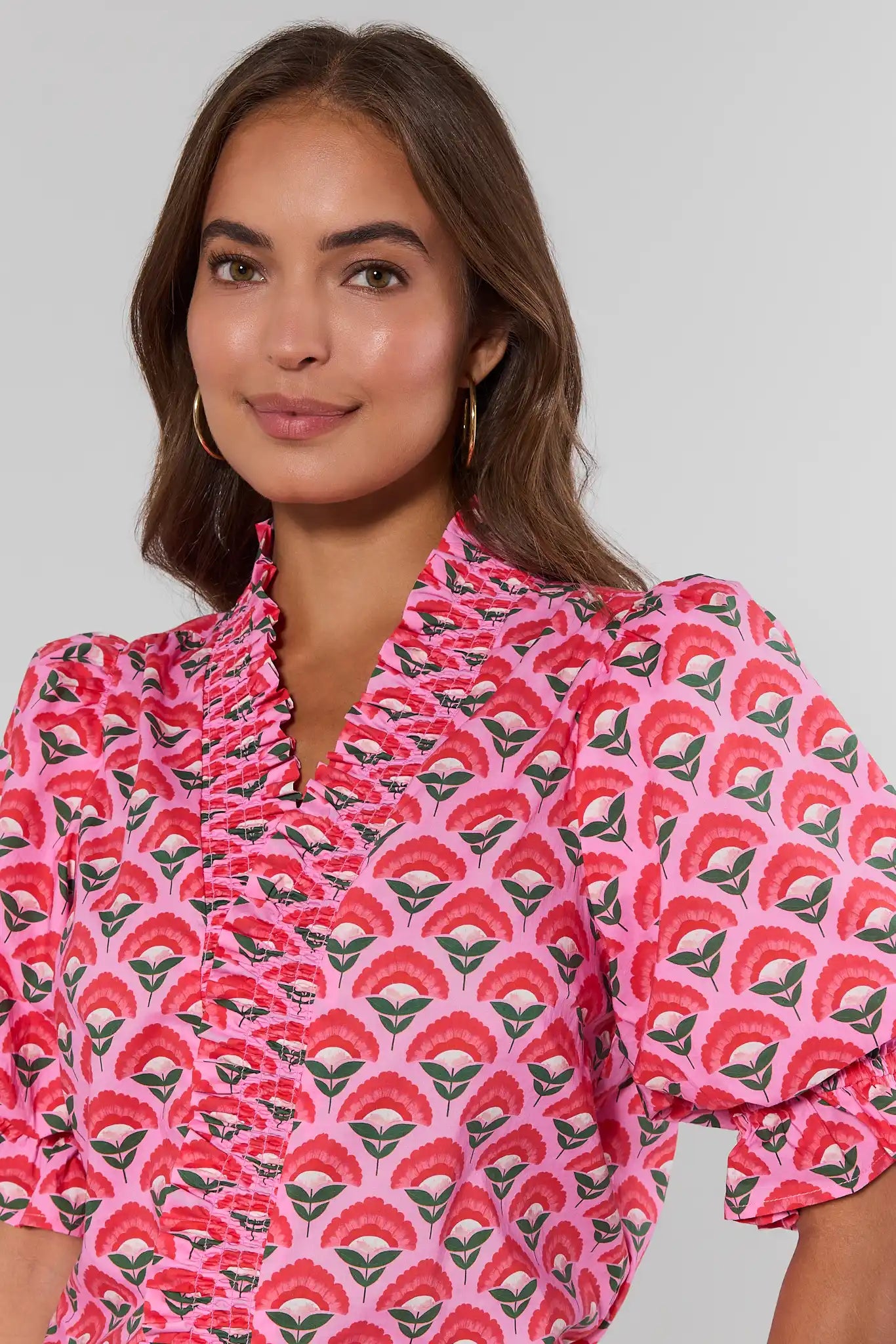 Woman wearing a pink patterned blouse against a plain background close up