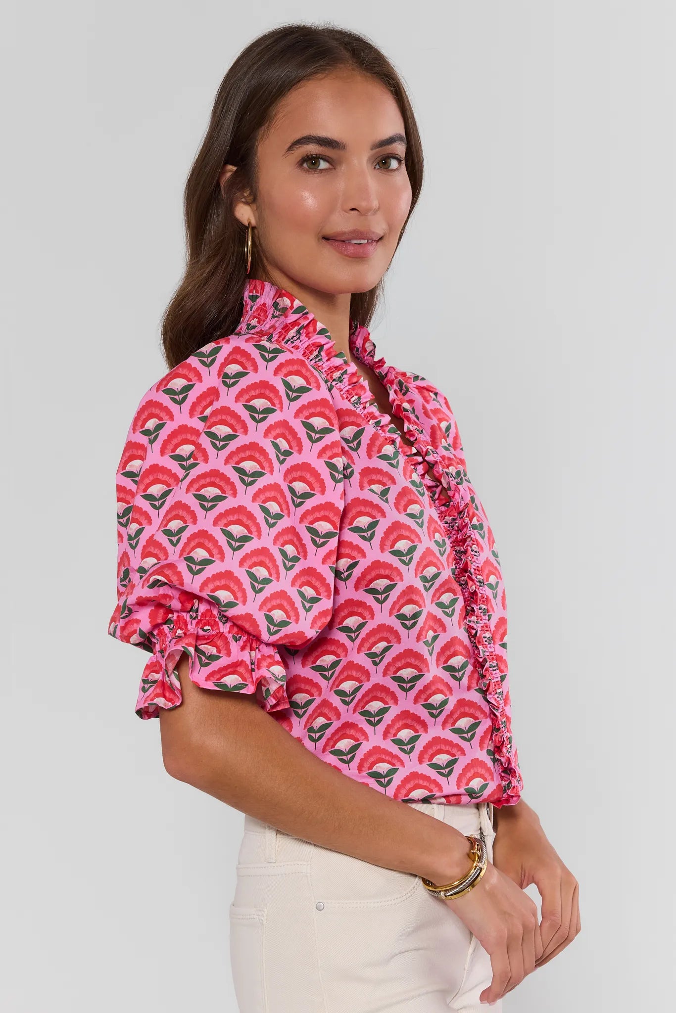 Woman wearing a pink patterned blouse with a white background side