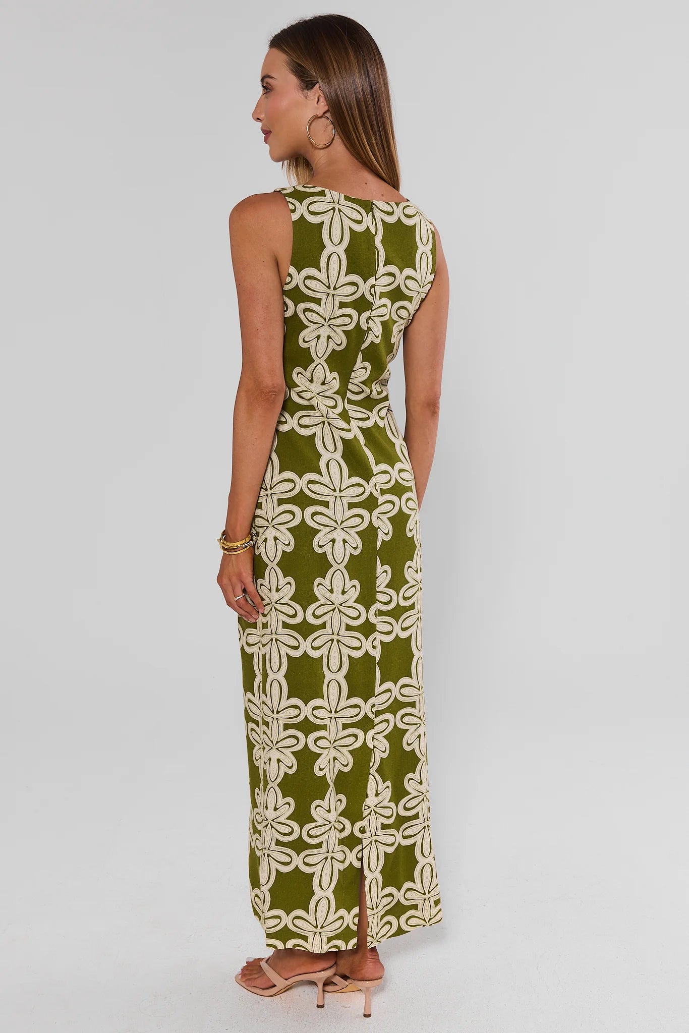 Woman wearing a green and white patterned dress on a plain background standing