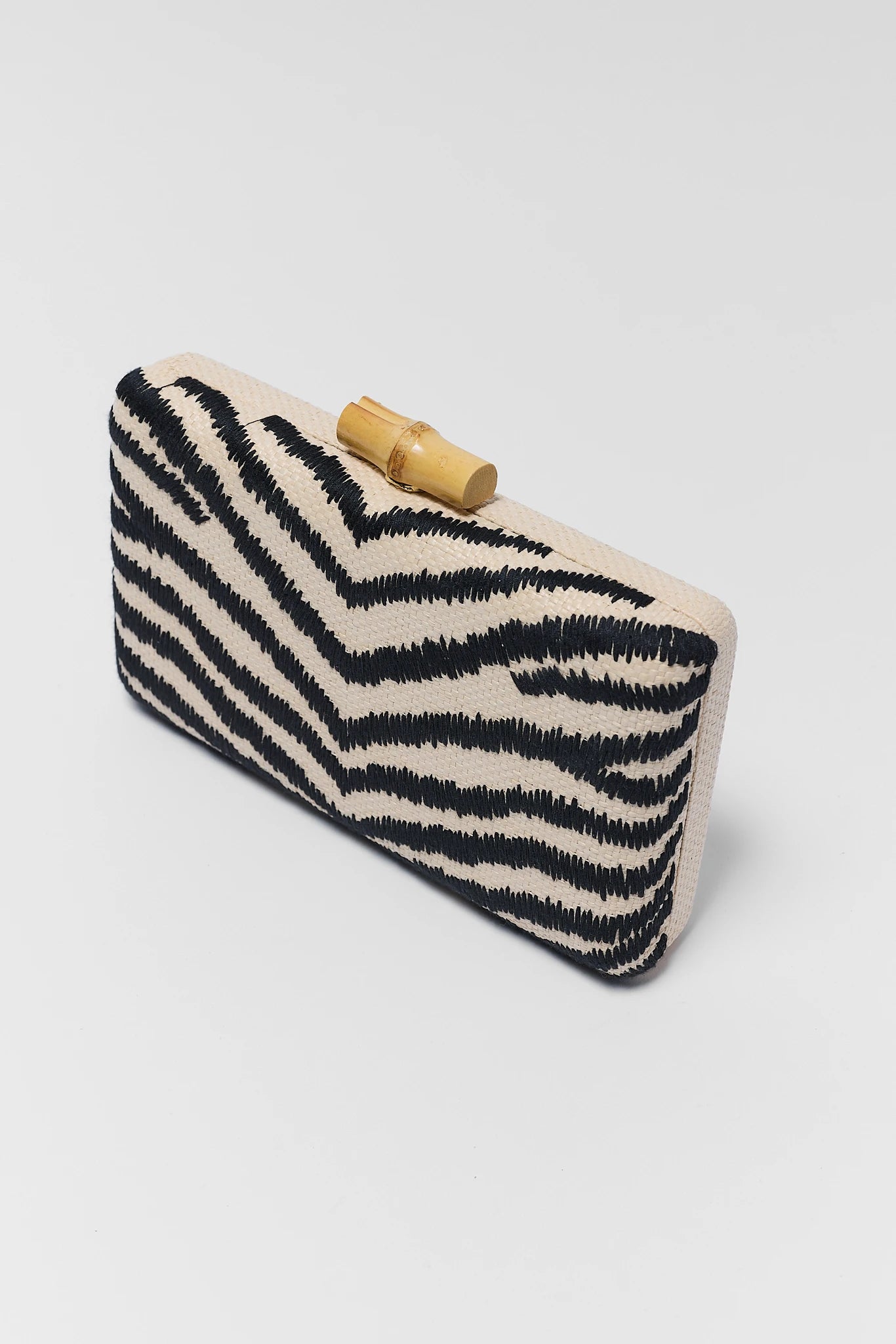 Clutch bag with zebra pattern and wooden clasp on a light gray background close up