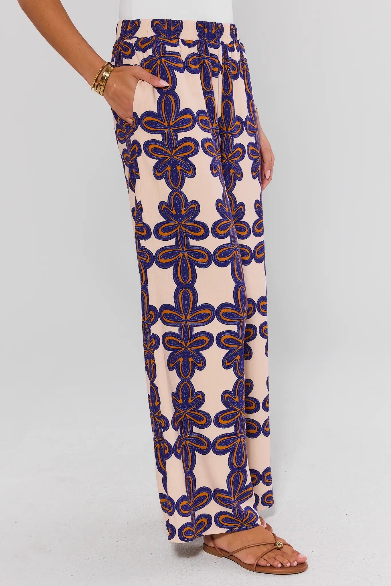 Beige pants with blue and orange geometric pattern worn by a person on a white background side