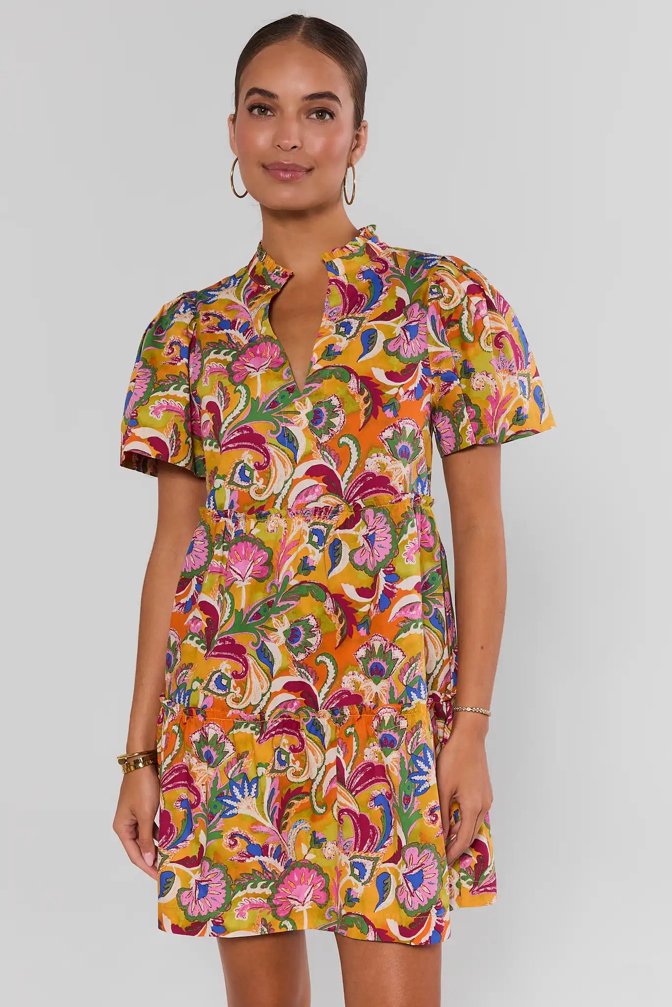 Woman wearing a colorful patterned dress on a plain background