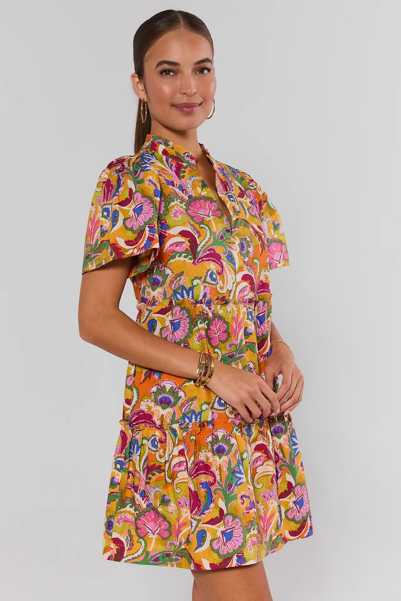 Woman wearing a colorful patterned dress on a plain background side
