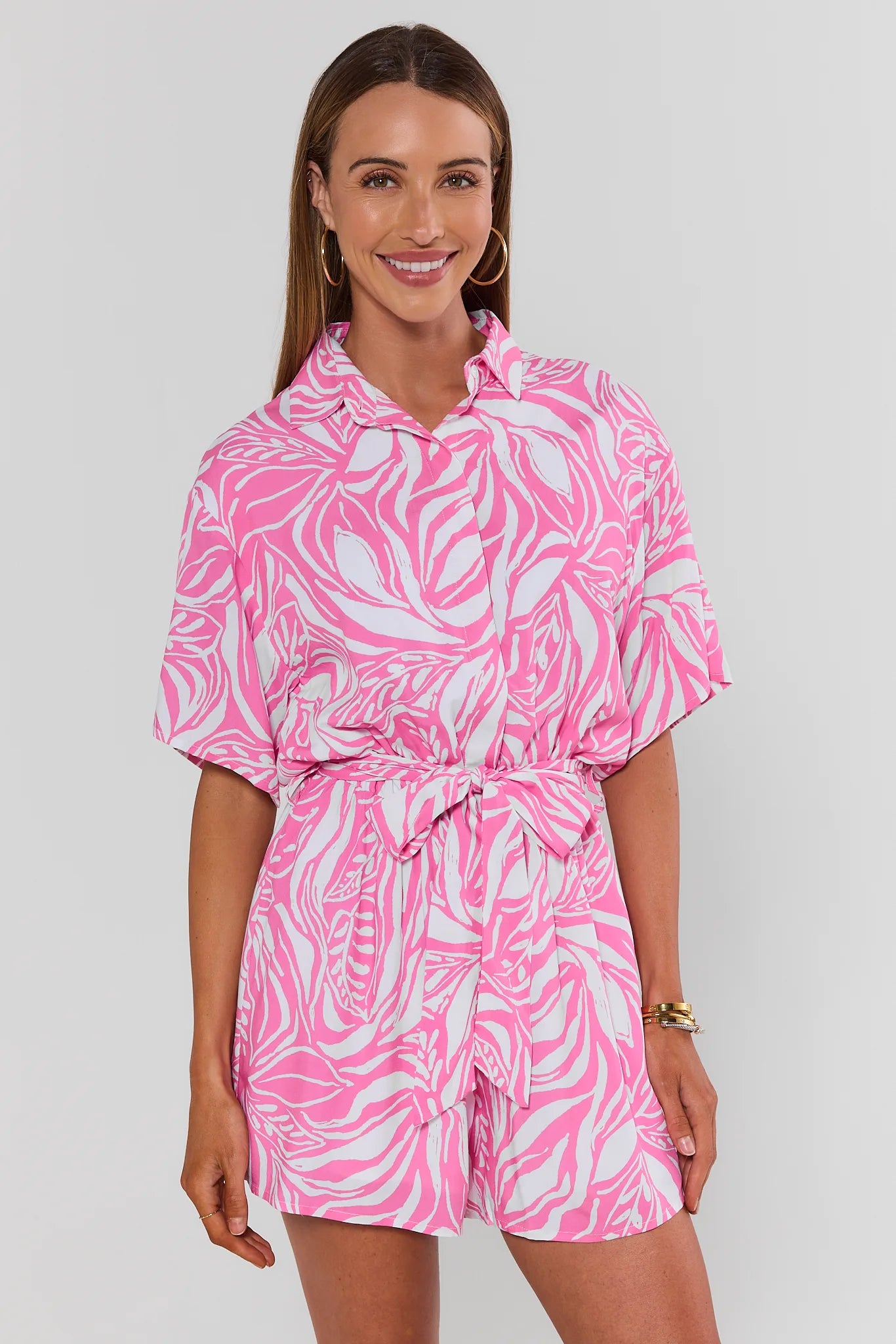 Woman wearing a pink and white patterned romper on a plain background