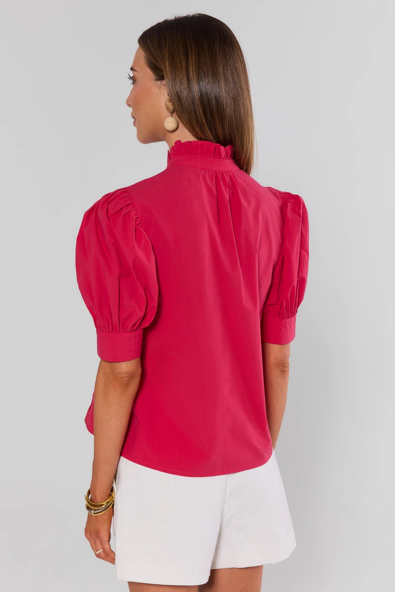 Woman standing wearing a pink blouse with puff sleeves on a background