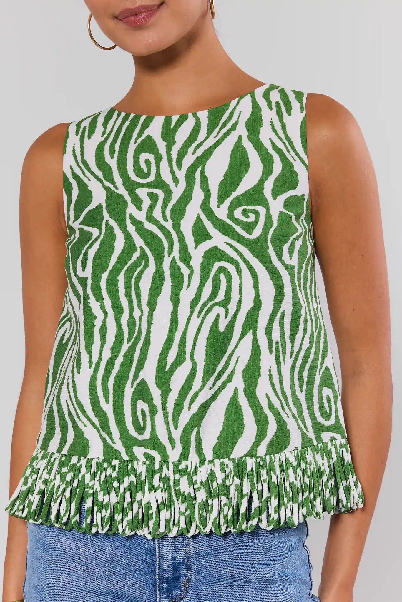 Green and white patterned sleeveless top worn by a person on a plain background close up