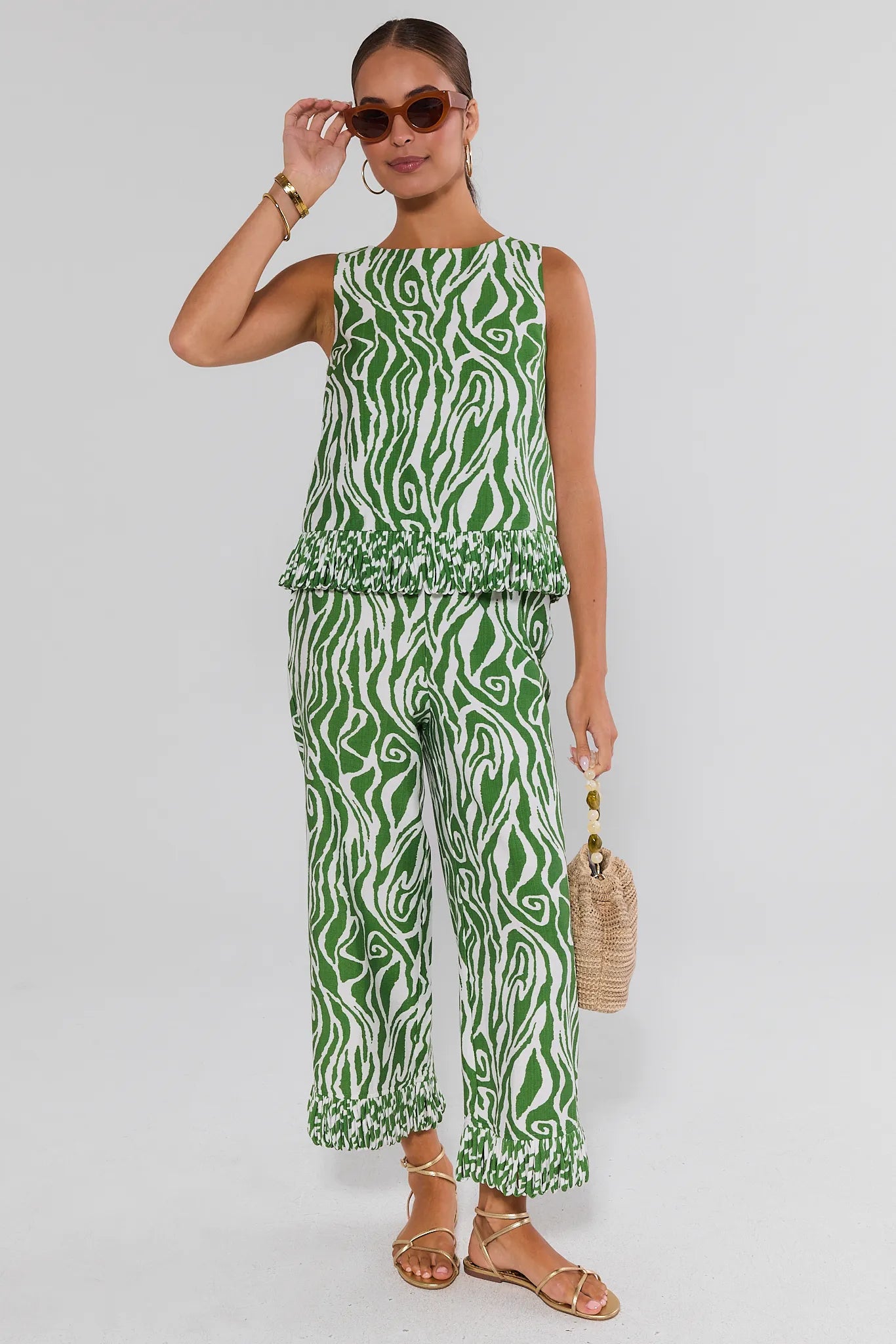 Woman wearing a green and white zebra print jumpsuit on a plain background