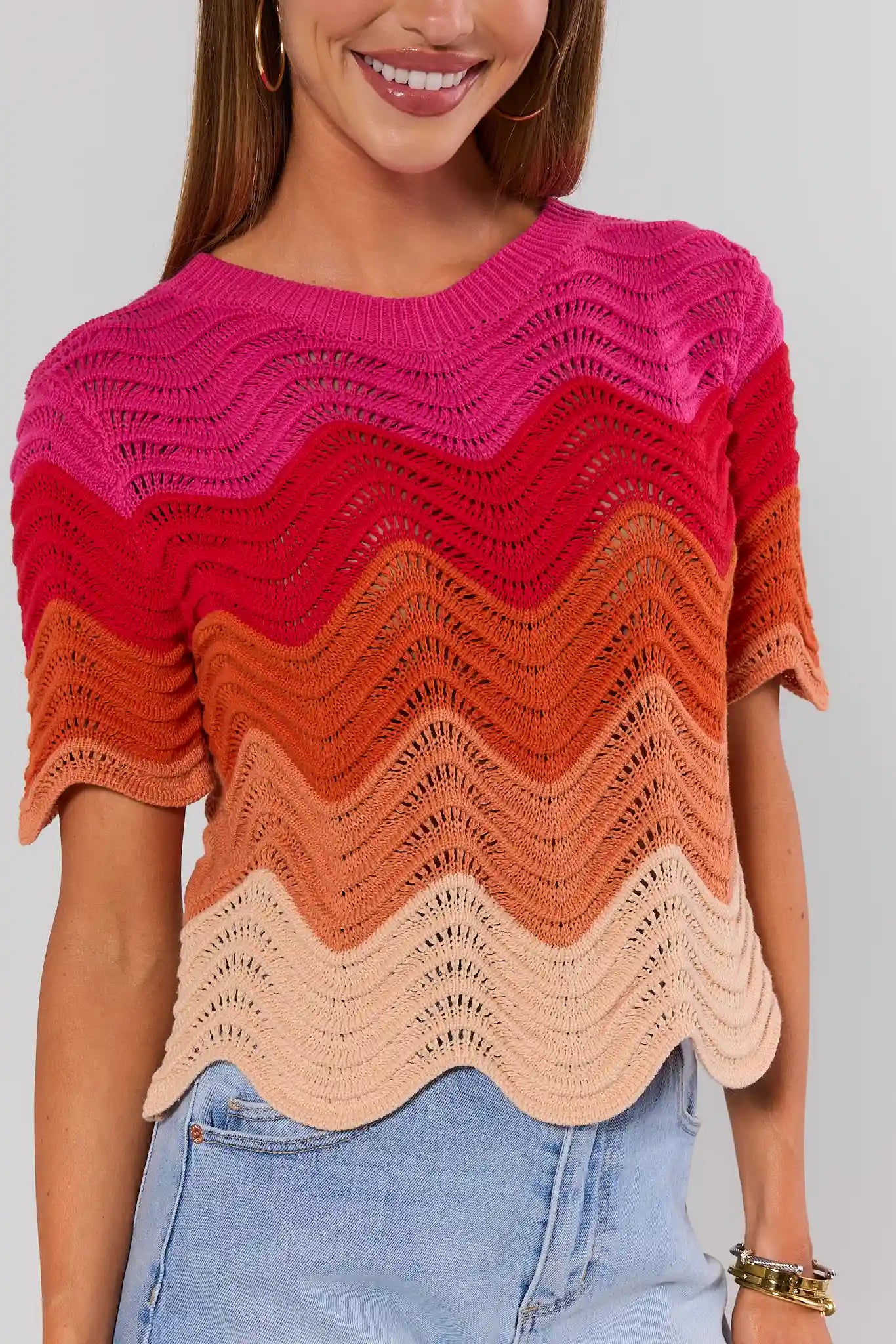 Woman wearing a colorful, patterned sweater with a plain background close up