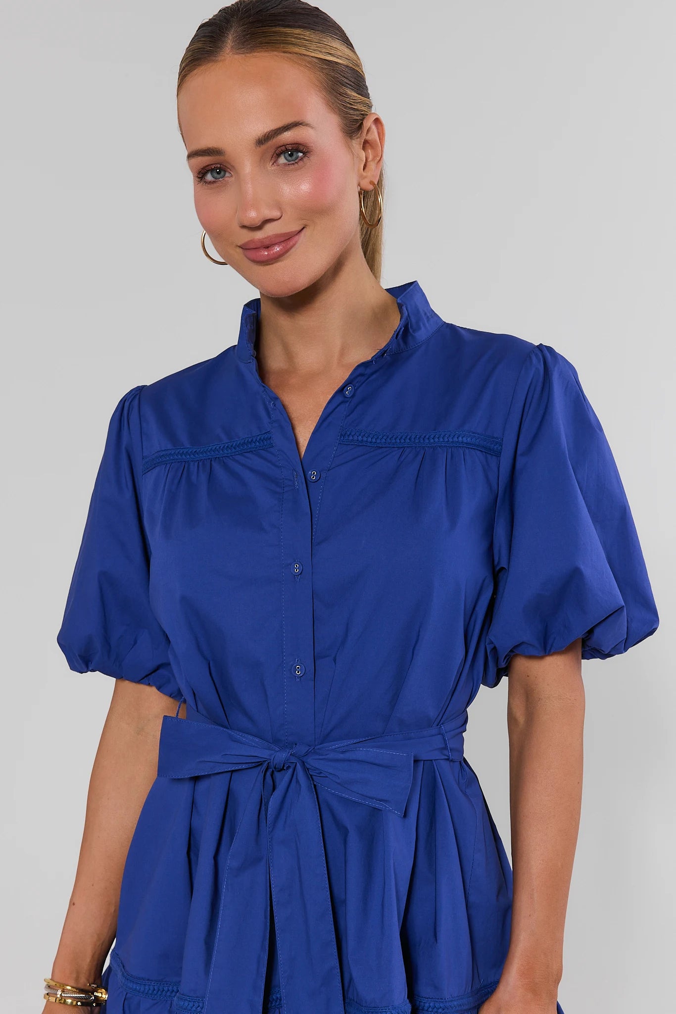 Woman wearing a blue dress against a plain background close up