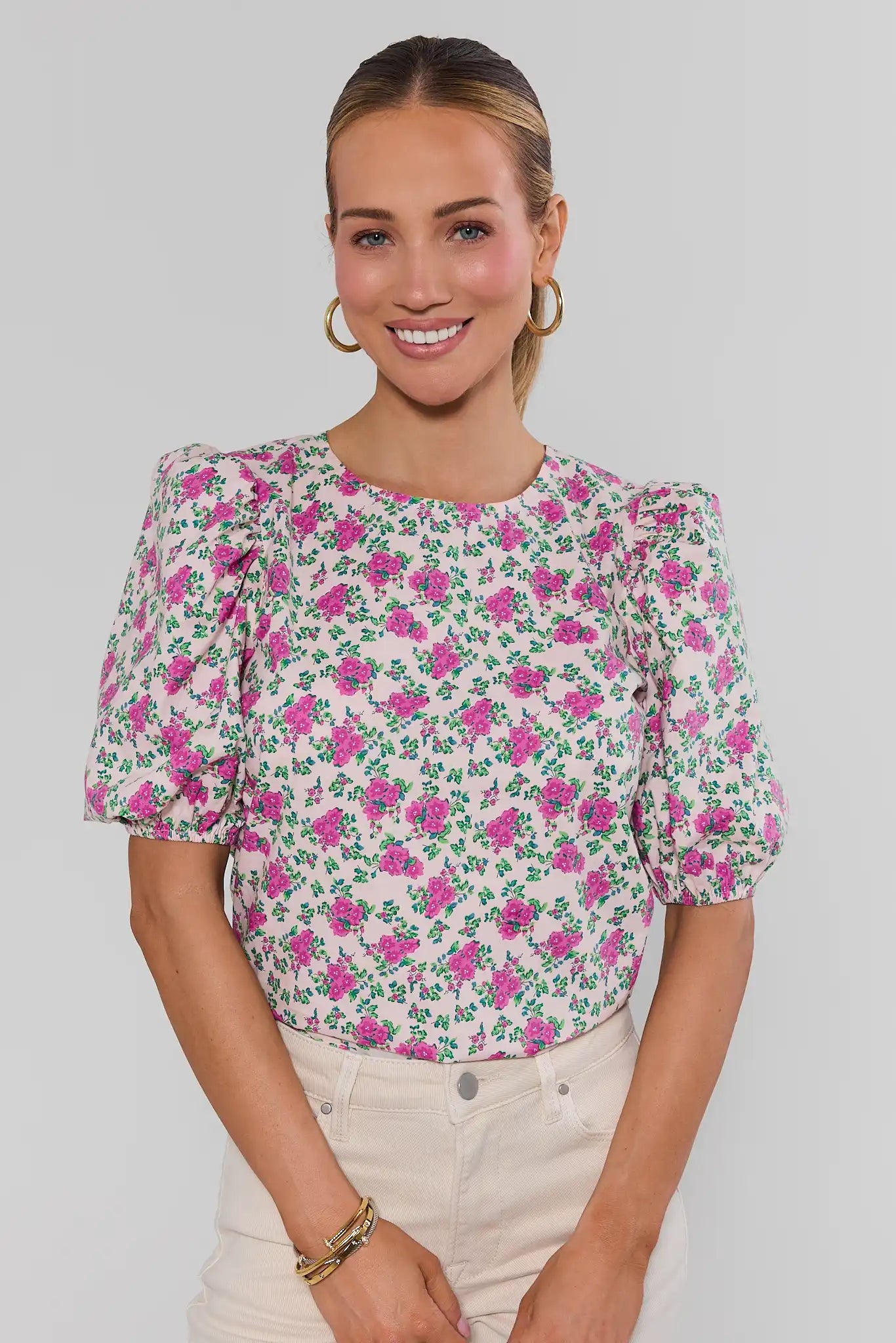 Woman wearing a floral blouse with a plain background standing