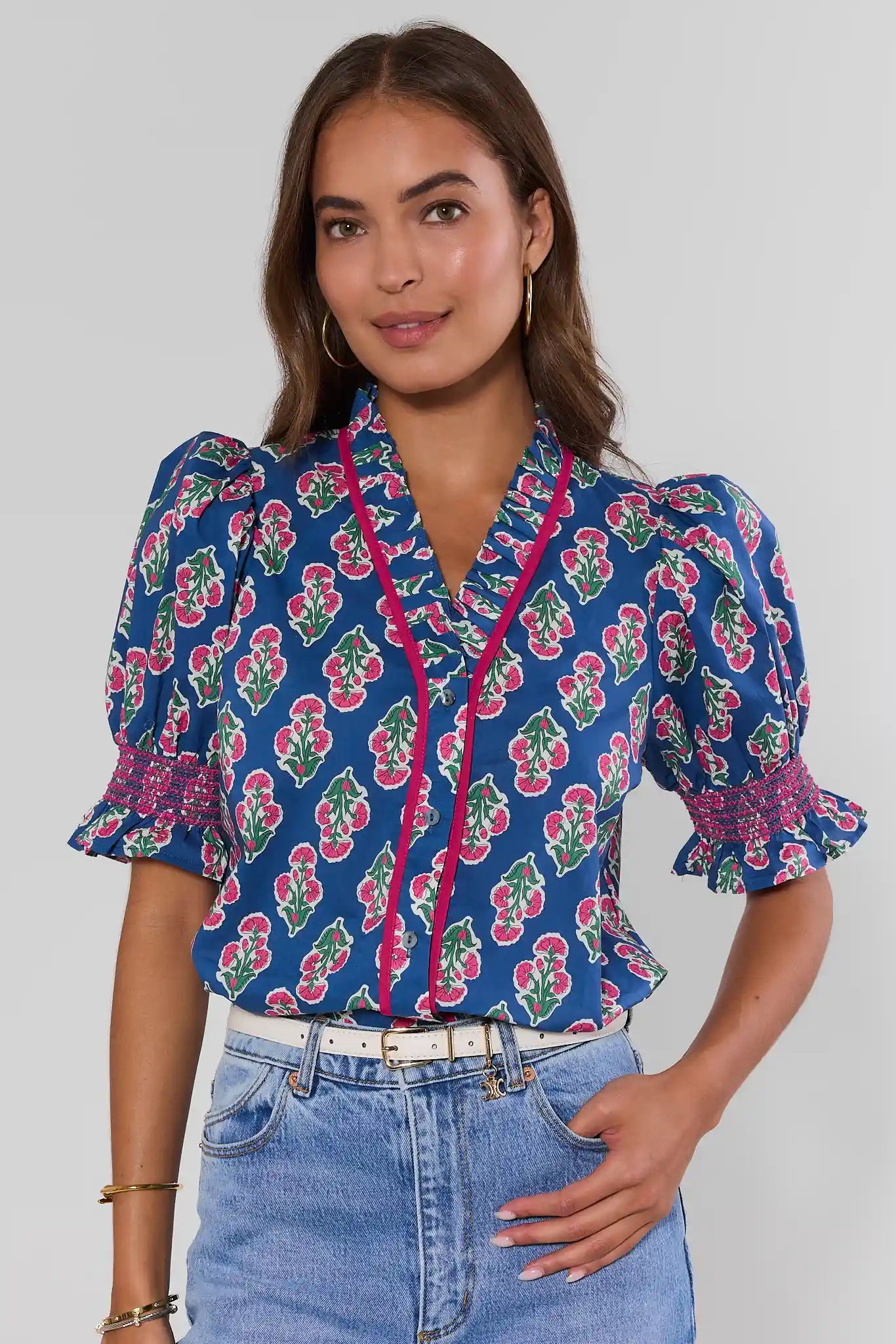Woman wearing a blue floral blouse with a plain background standing