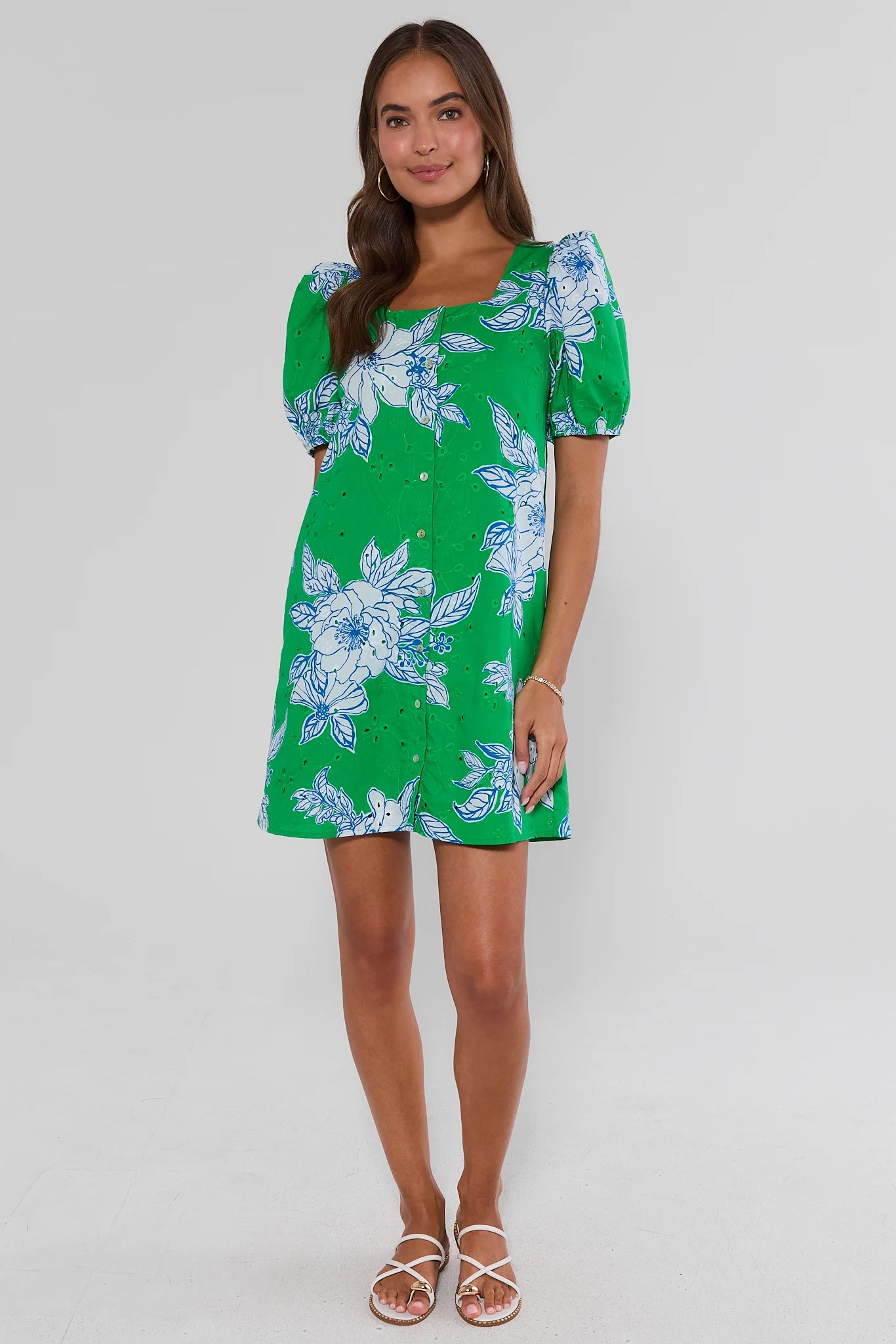 Woman walking wearing a green floral dress on a white background