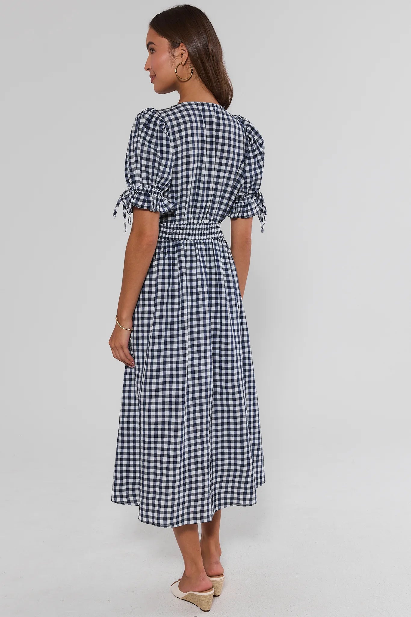 Woman standing wearing a black and white checkered dress on a plain background