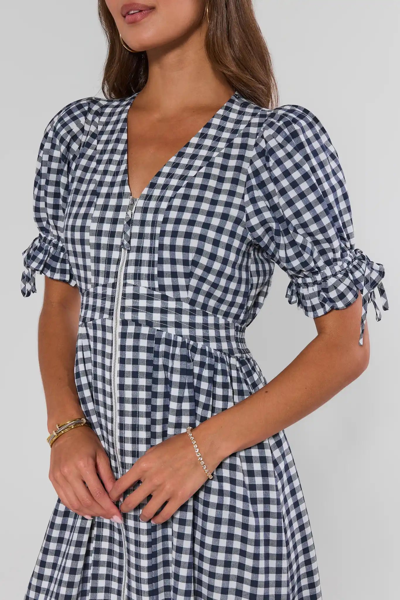 Woman wearing a blue and white checkered dress against a plain background close up