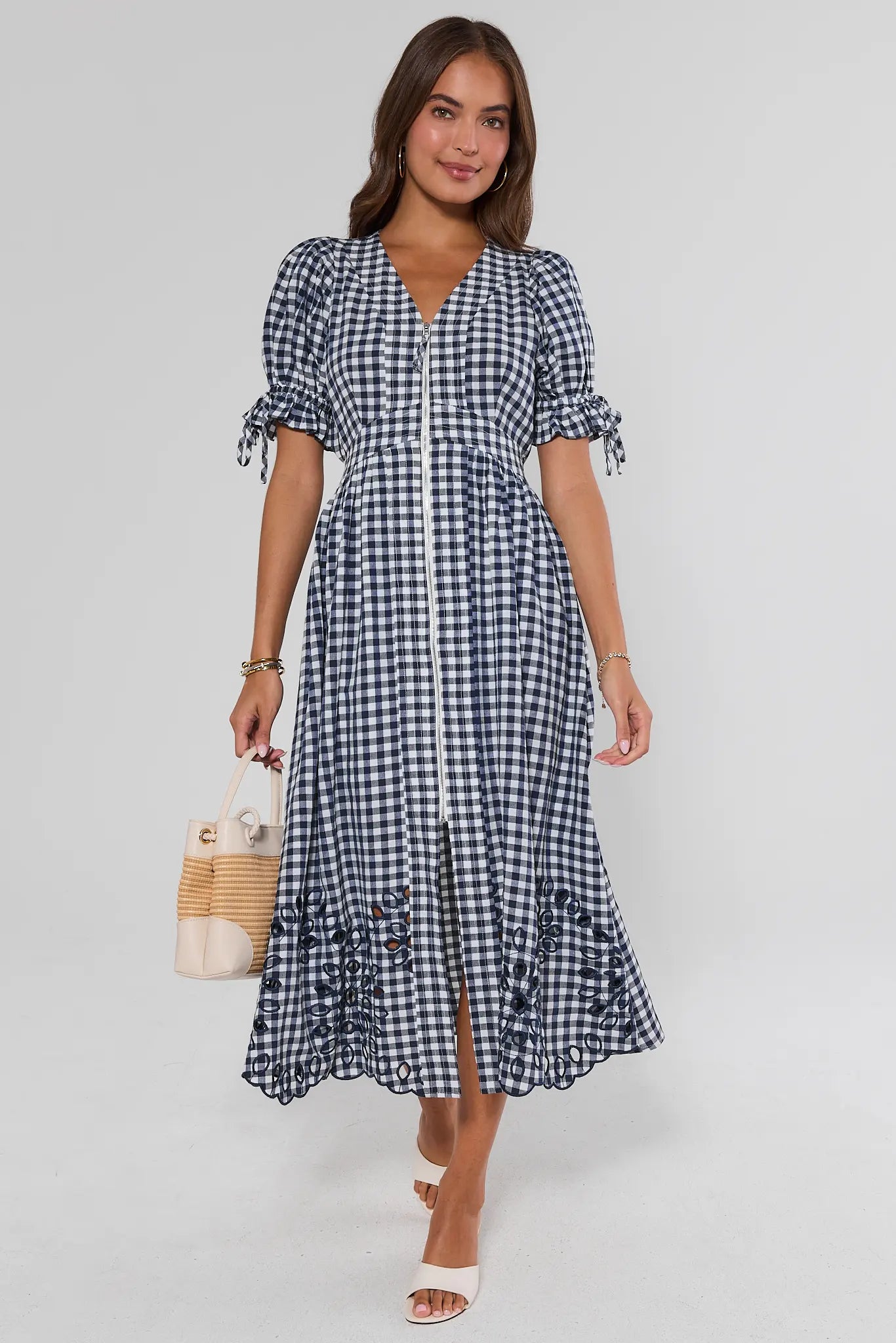 Woman wearing a blue and white checkered dress on a gray background walking