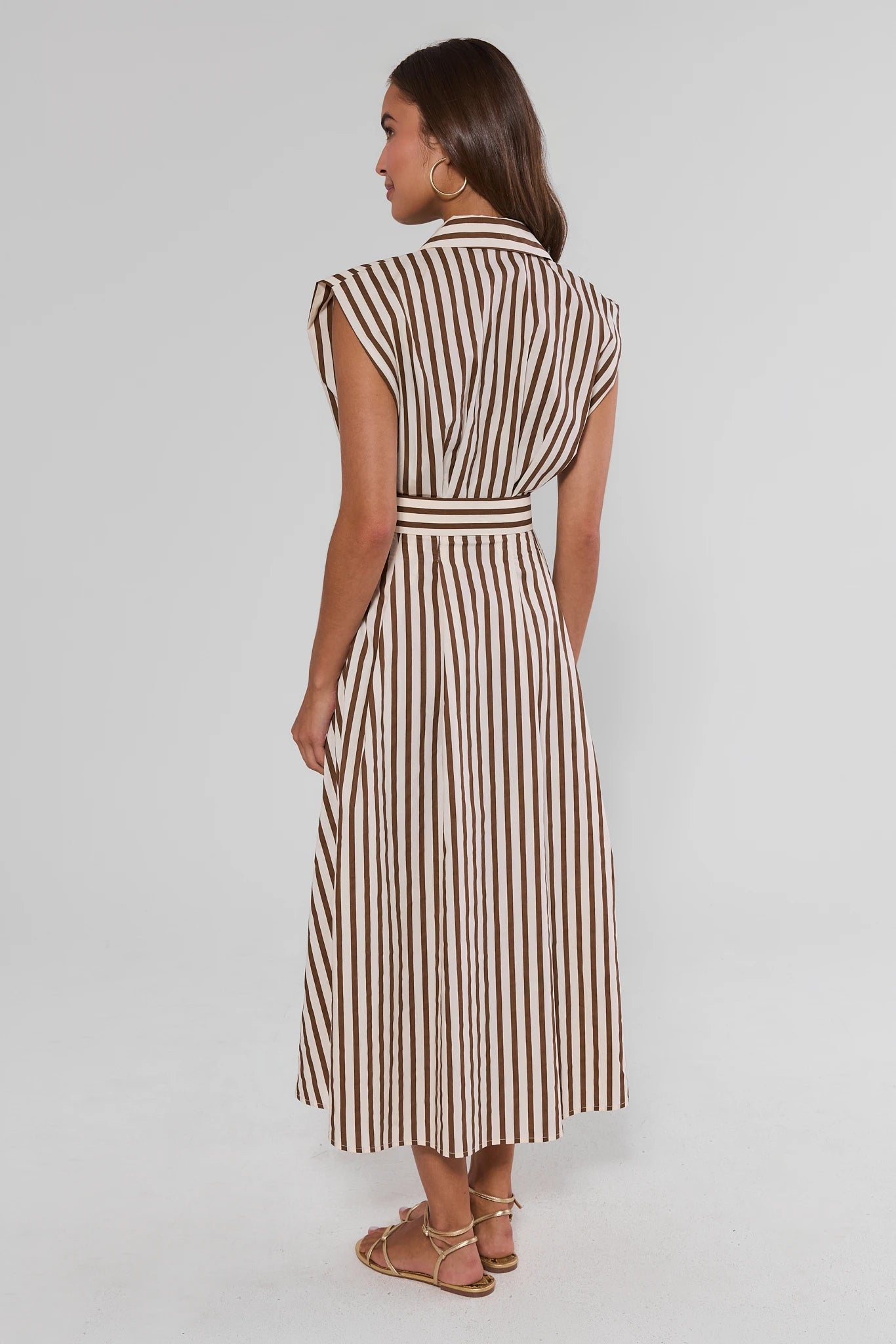 Woman standing wearing a striped dress on a white background