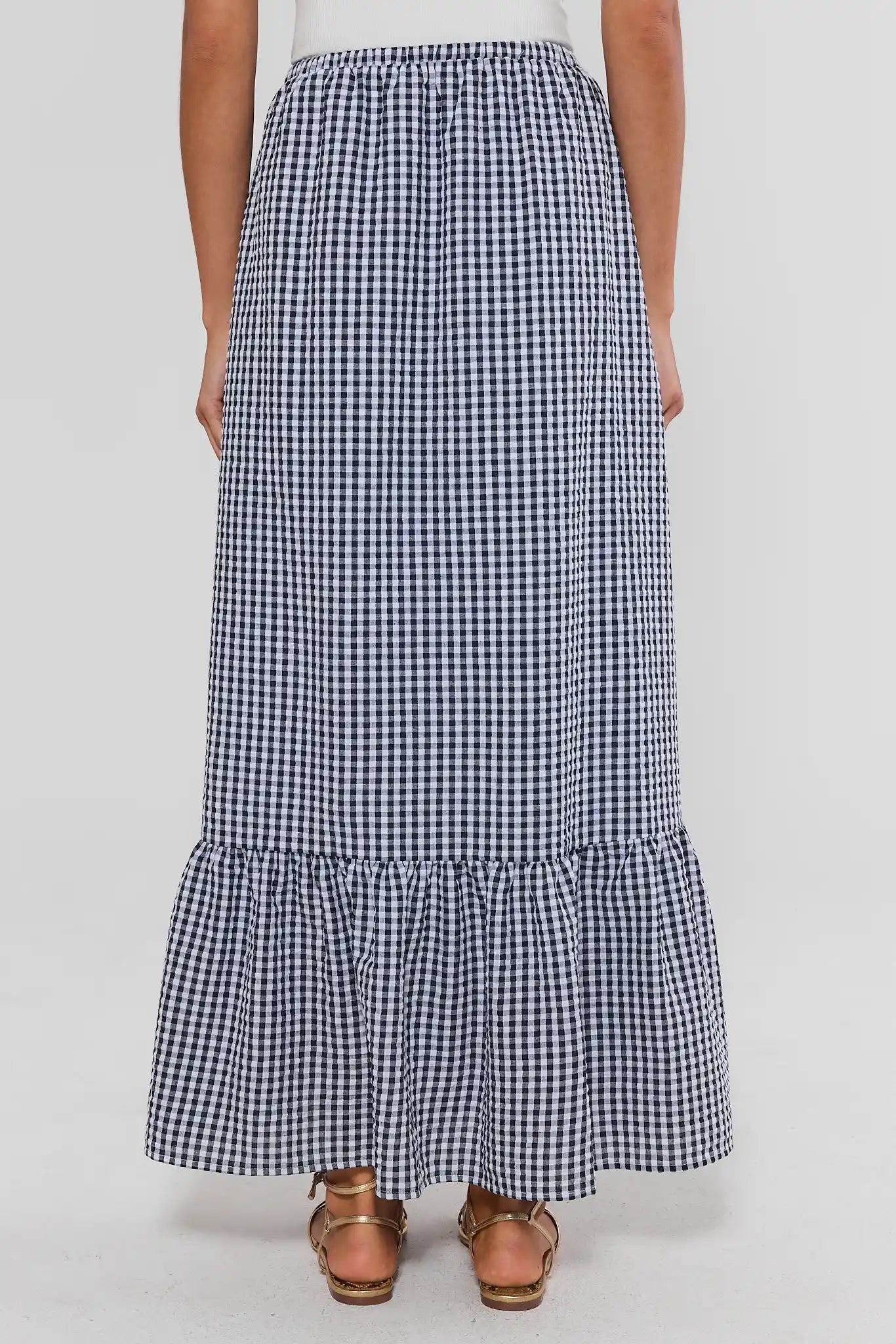 Person wearing a black and white checkered skirt on a plain background standing