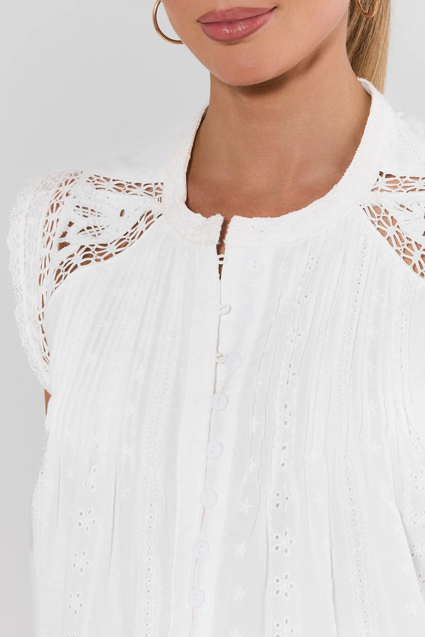 White lace-trimmed top worn by a model on a plain background close up