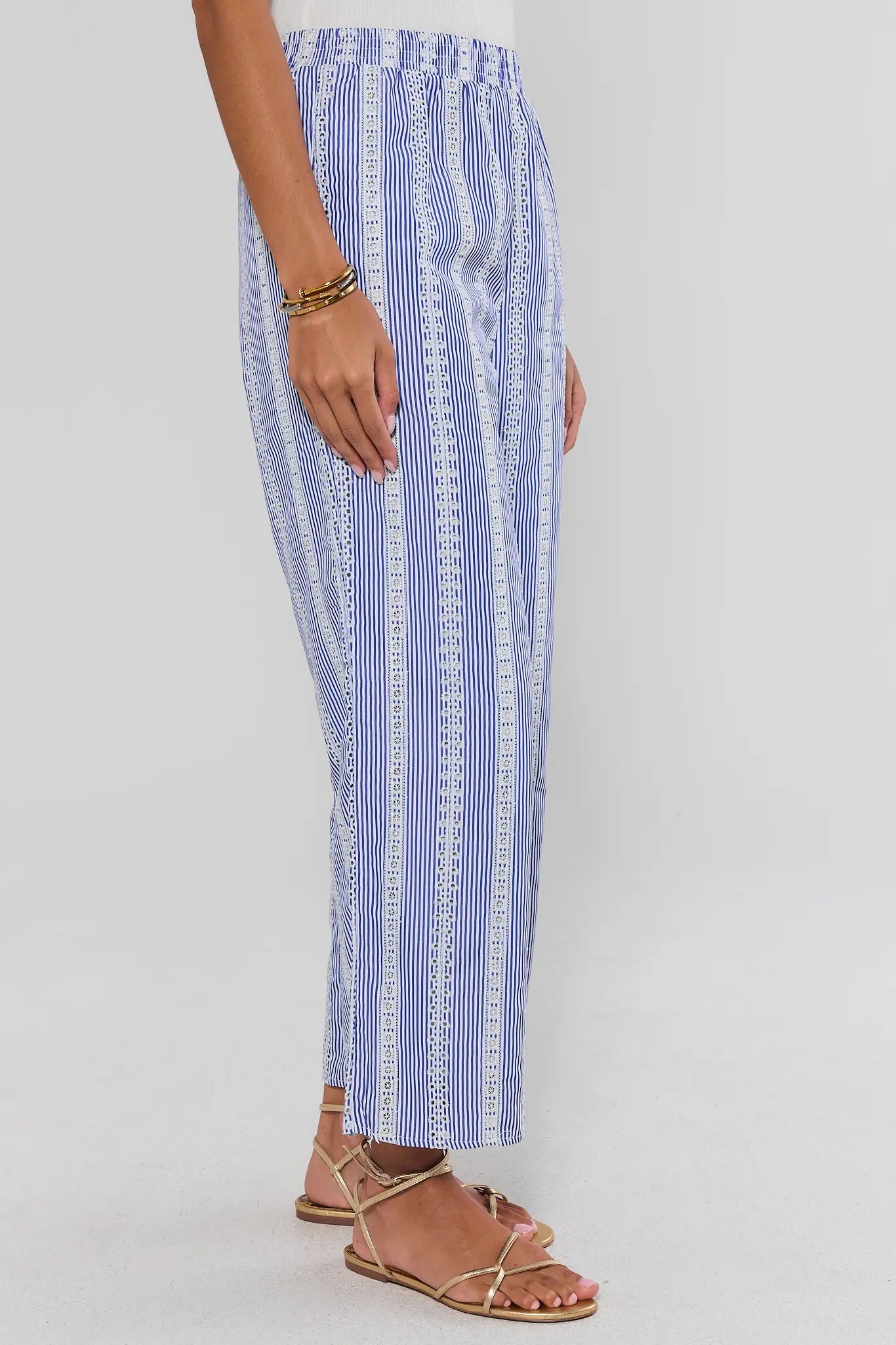 Blue and white striped pants worn by a person on a light gray background side
