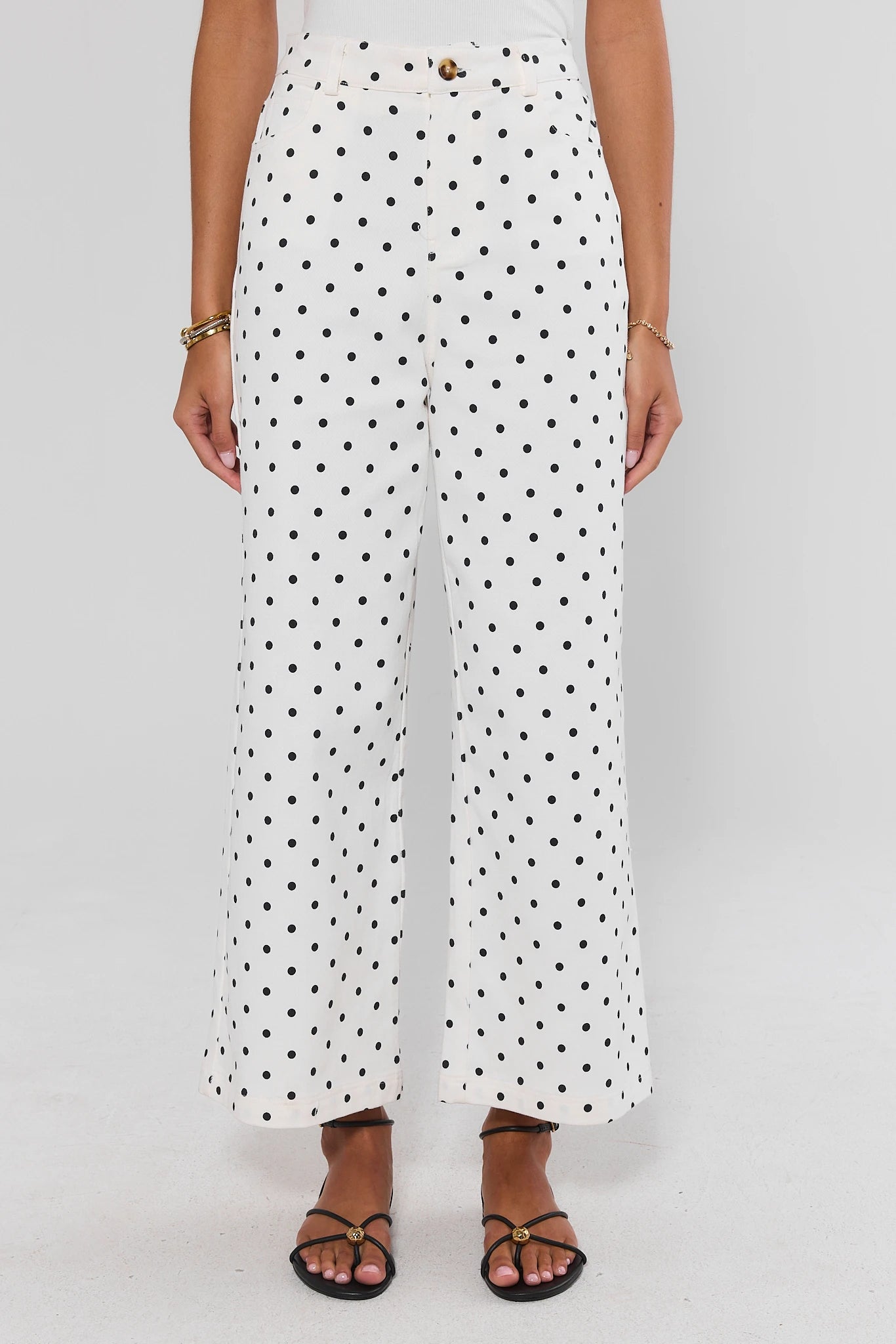 Person wearing white pants with black polka dots on a plain background