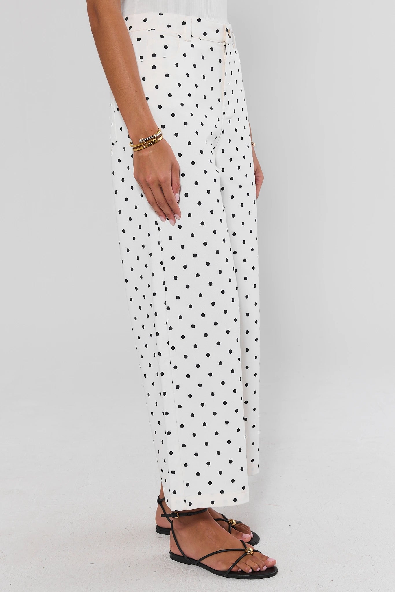 White pants with black polka dots worn by a person on a white background standing
