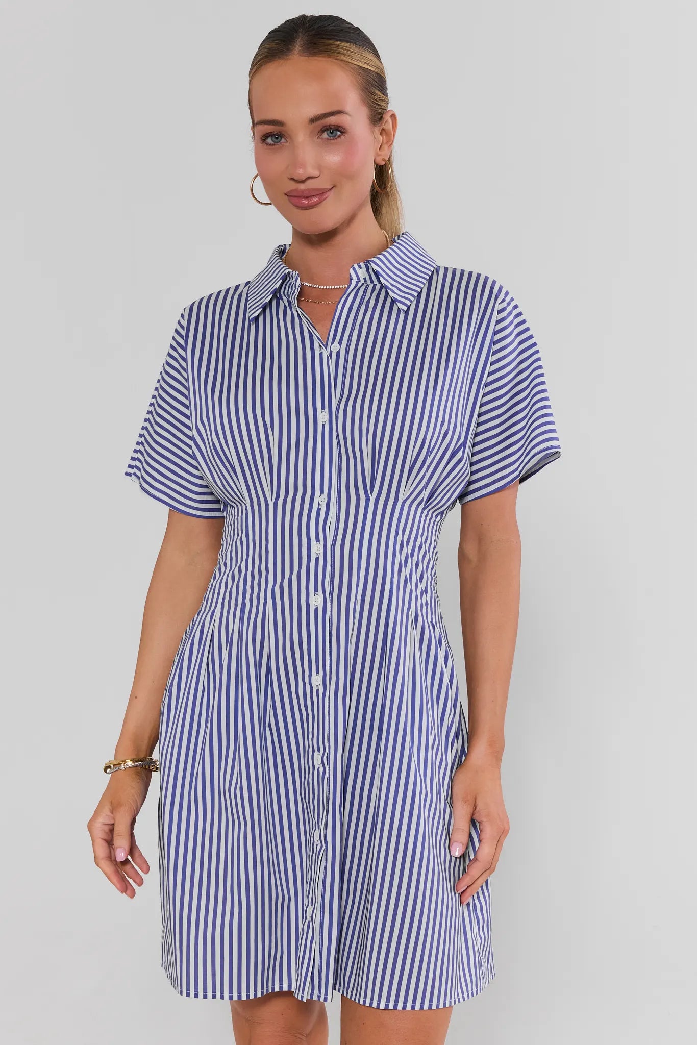 Woman wearing a blue and white striped shirt dress against a plain background