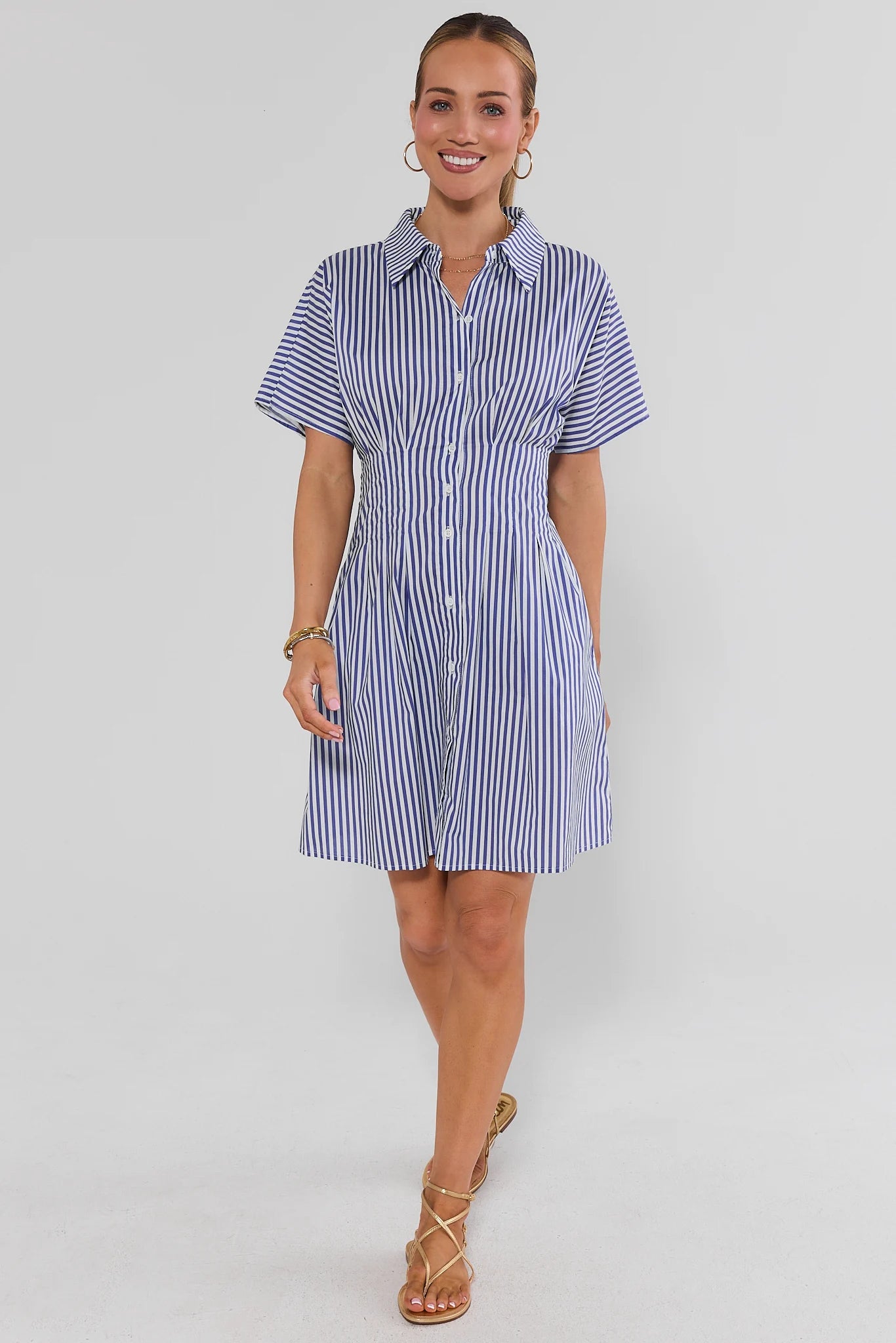 Woman wearing a blue and white striped dress on a gray background standing