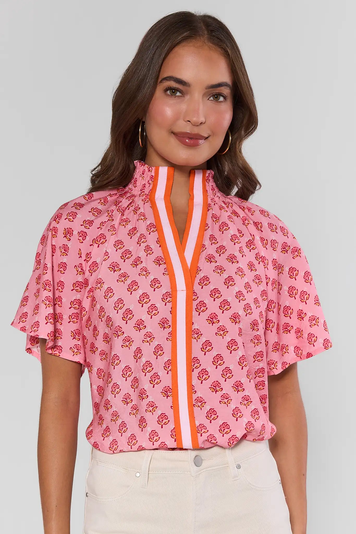 Woman wearing a pink floral blouse with a white background lifestyle