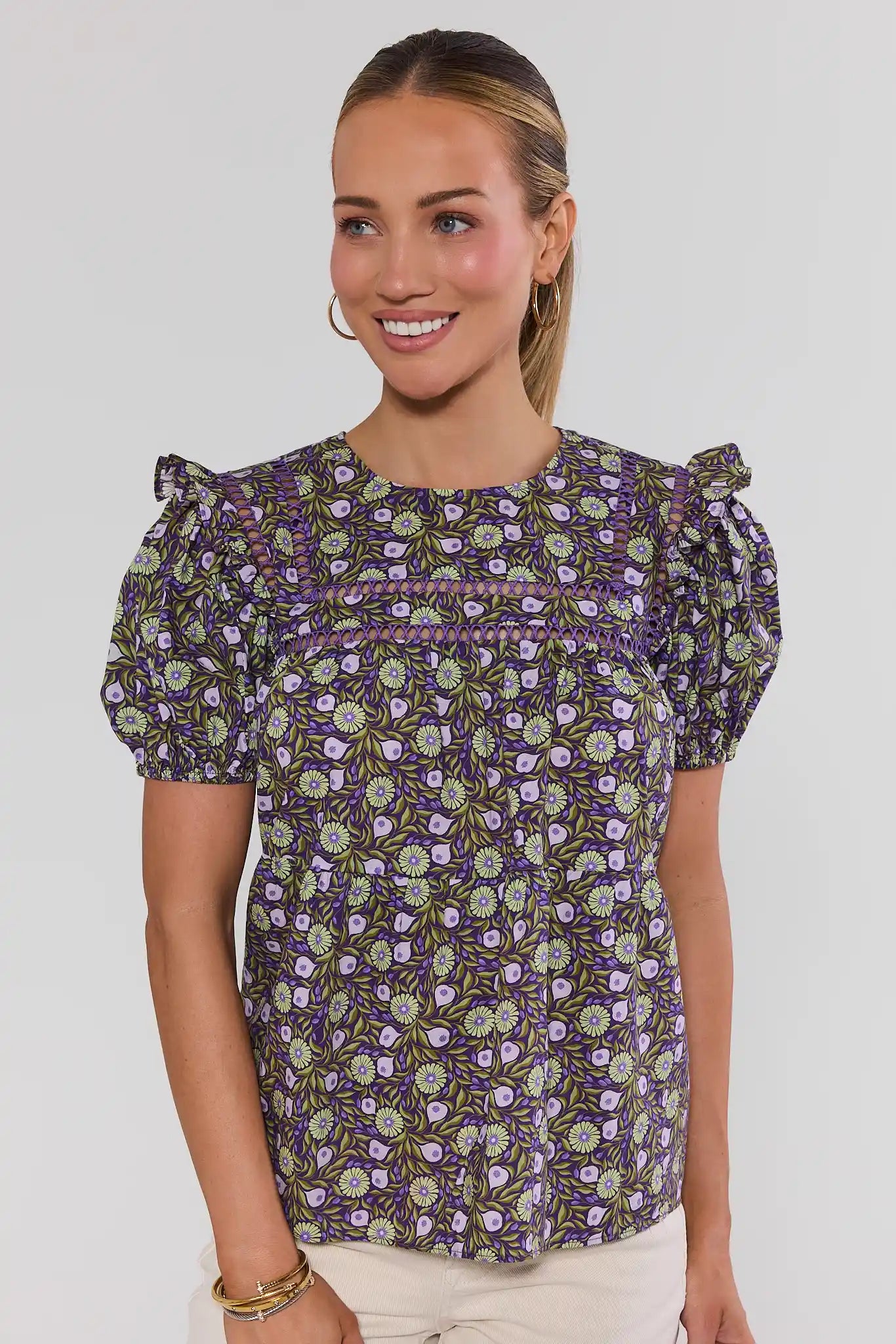 Woman wearing a floral blouse with puff sleeves against a plain background